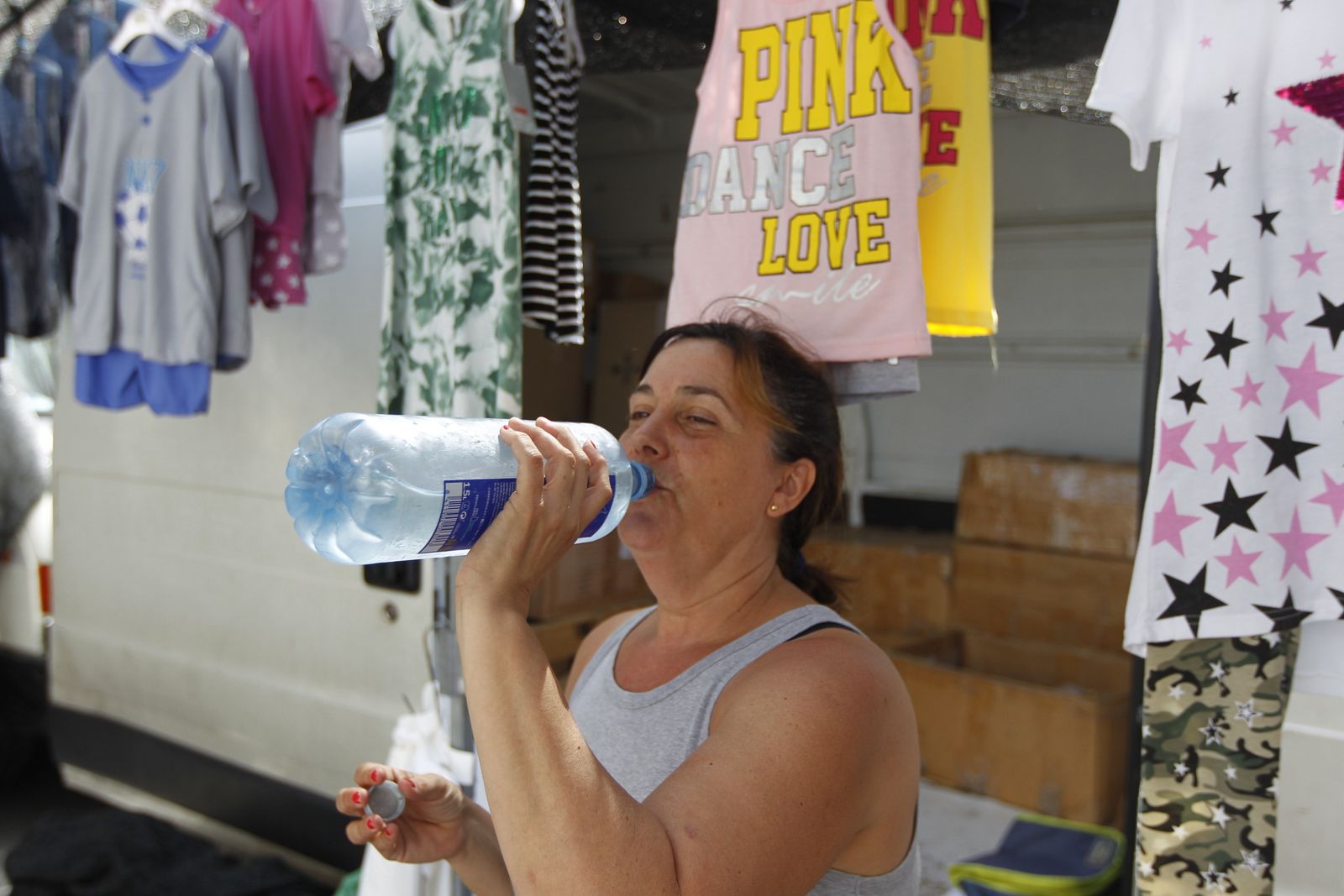Nuria Mesas remedia el calor bebiendo agua en su puesto del mercadillo.