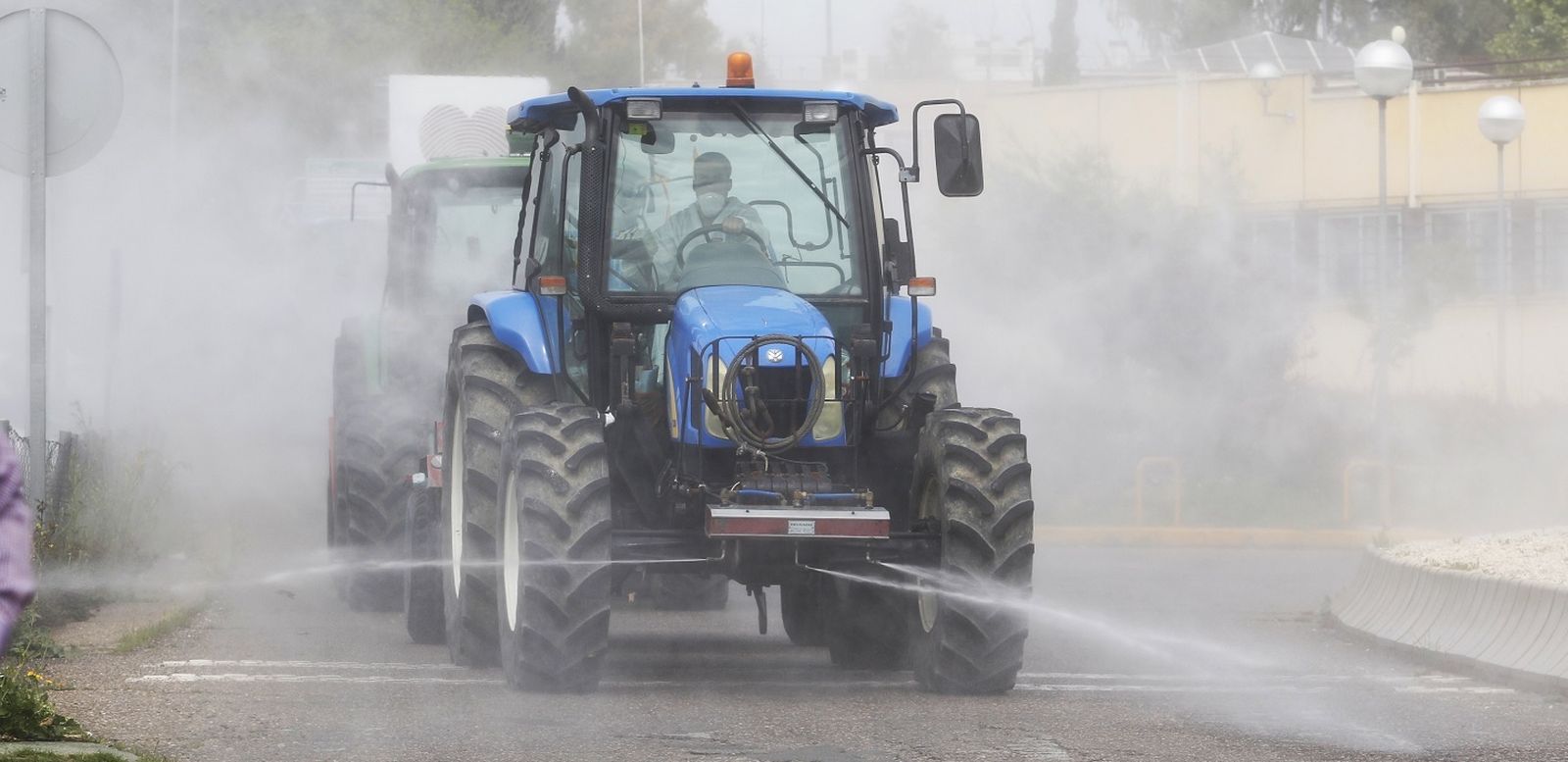 Tractores esparcen el desinfectante a su llegada a las inmediaciones del Hospital Reina Sofía.