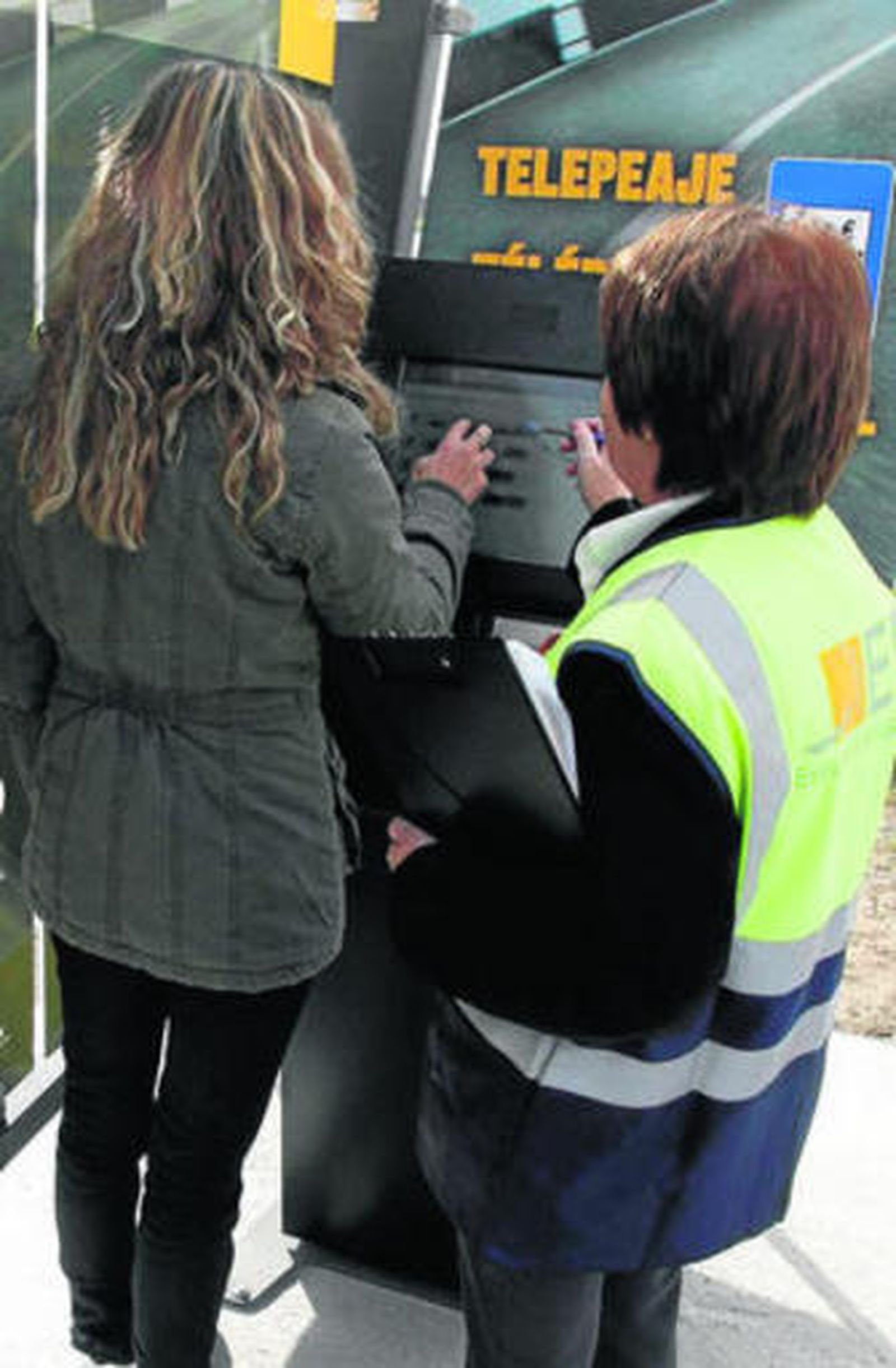 Una operaria muestra a una usuaria cómo sacar el tique de la autovía.