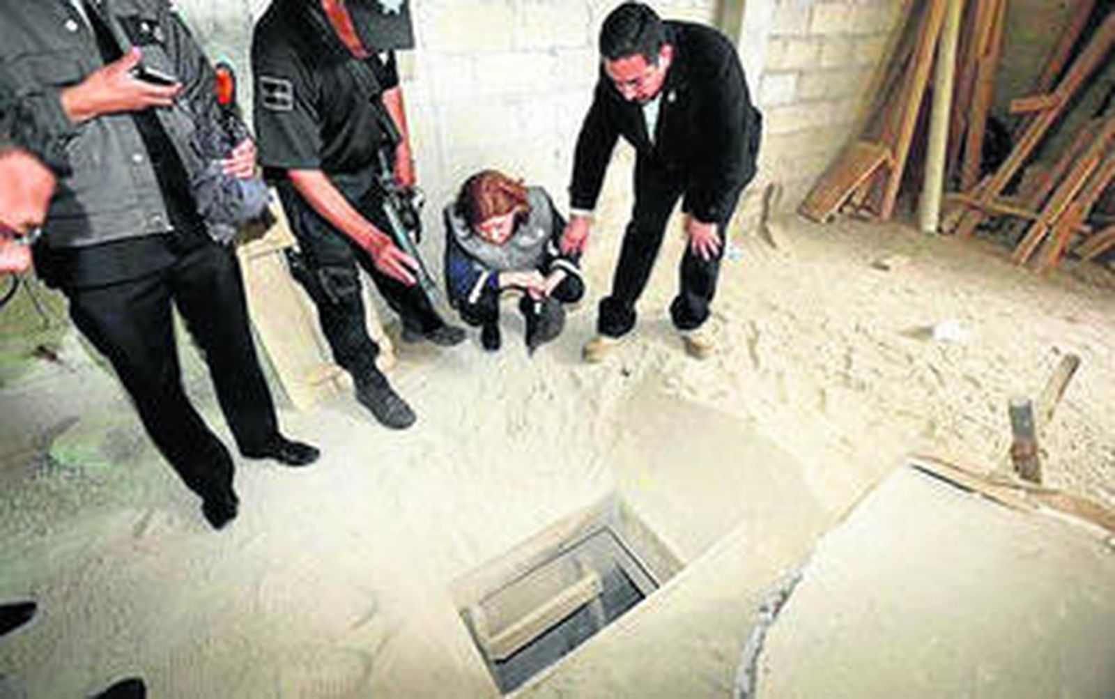 La procuradora general (fiscal), Arely Gómez -agachada-, observa la entrada al túnel por el que escapó Joaquín Guzmán.