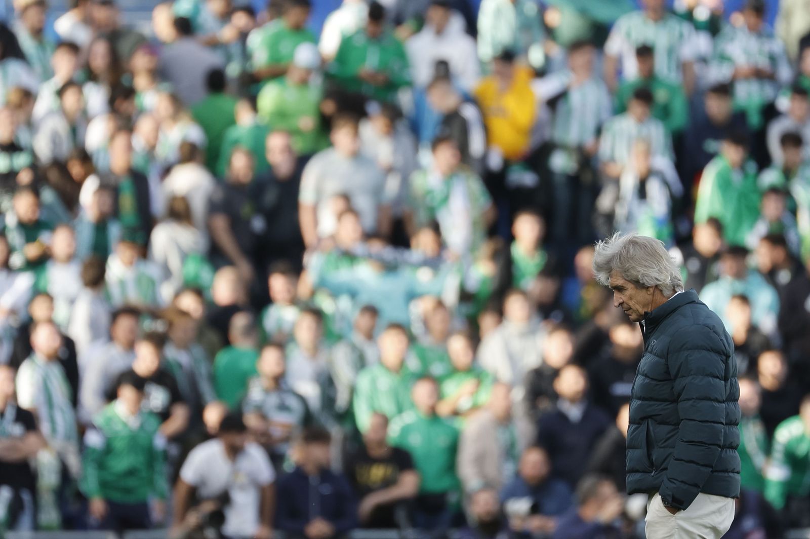 Pelllegrini, pensativo con los aficionados del conjunto verdiblanco al fondo, durante un momento del partido del Betis del pasado sábado en casa del Getafe.