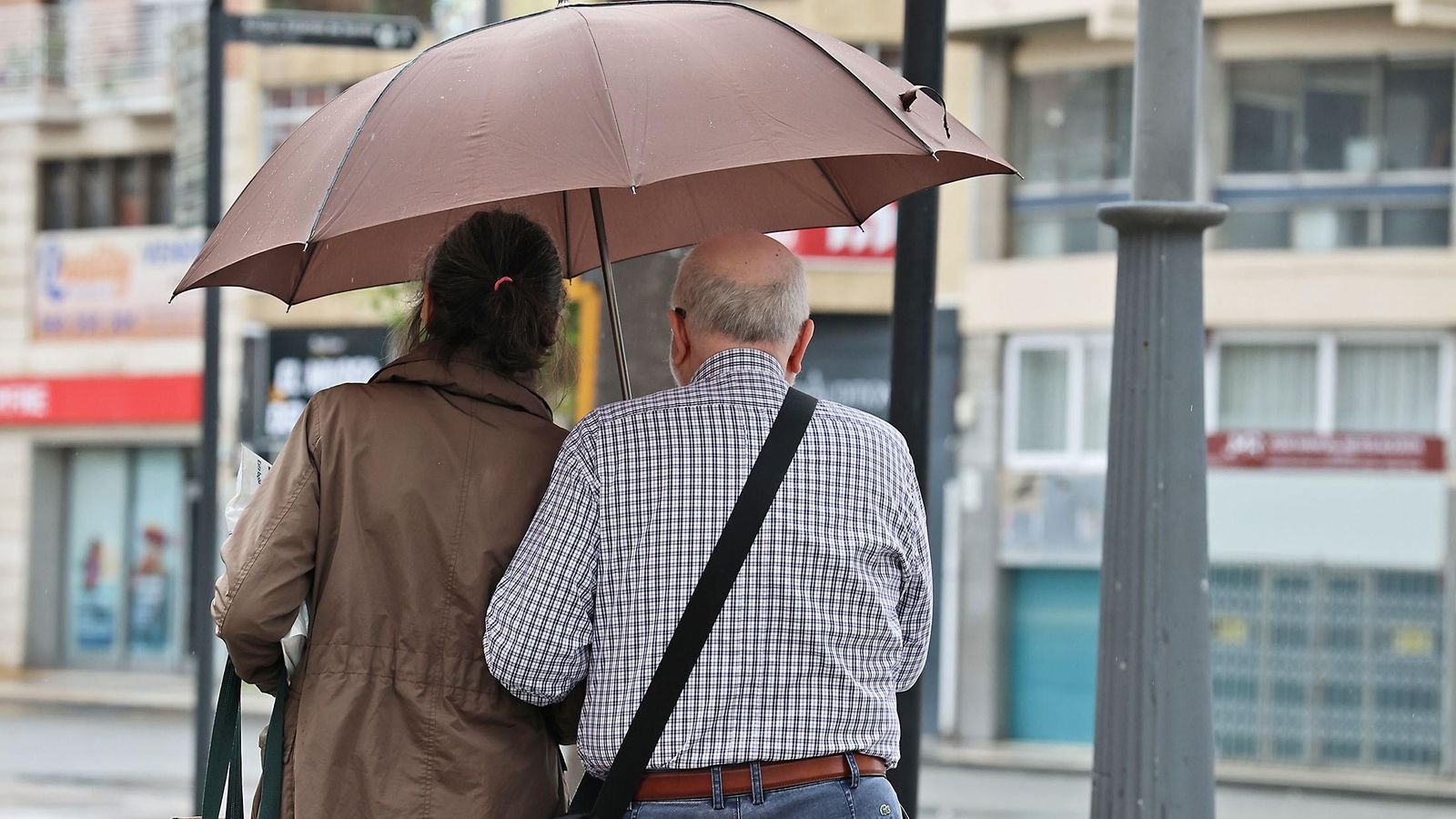 Dos personas con un paraguas por las calles de Hueva.