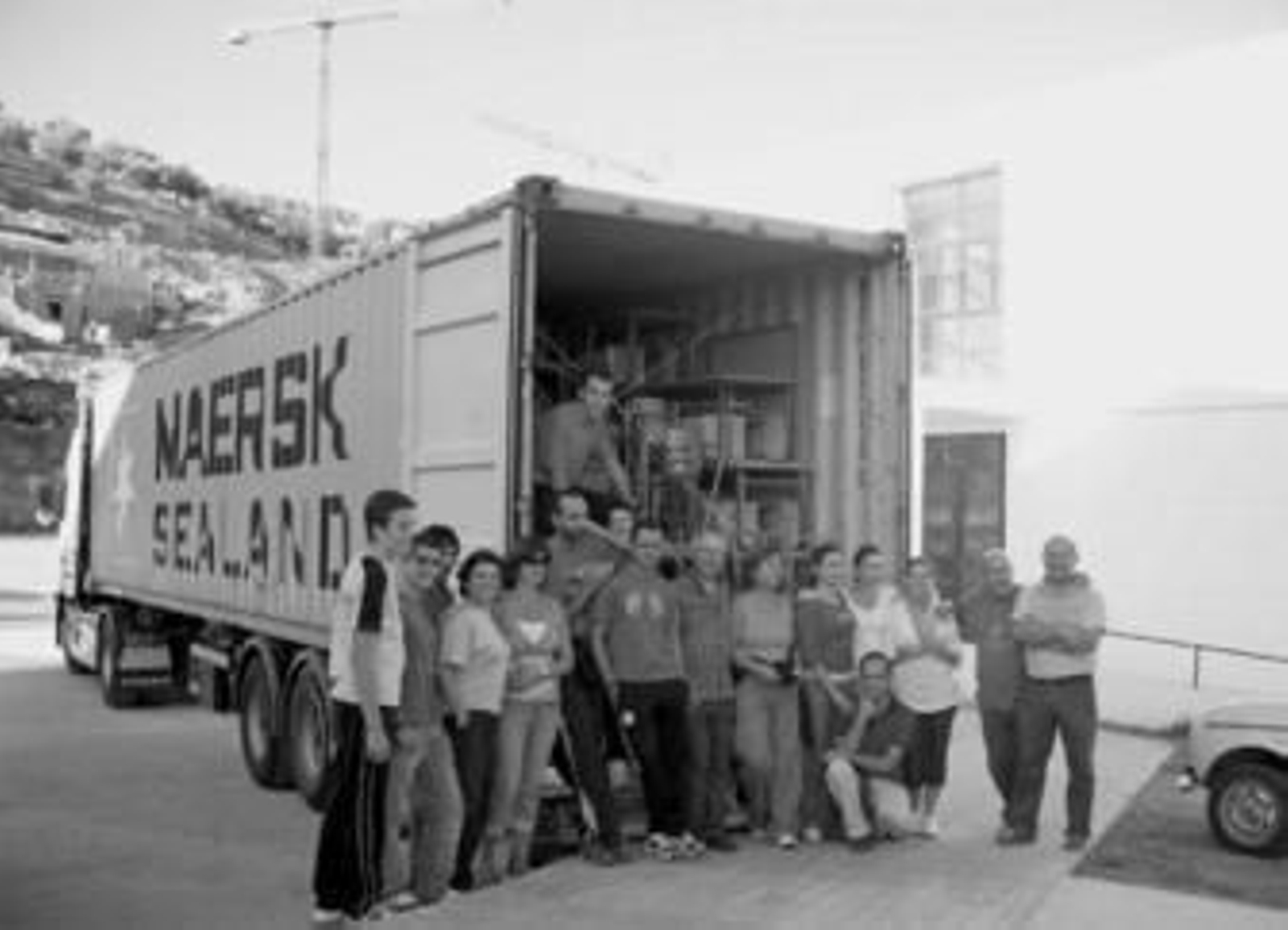 Los colaboradores de la ONG, junto con el camión que contiene todos los materiales escolares.