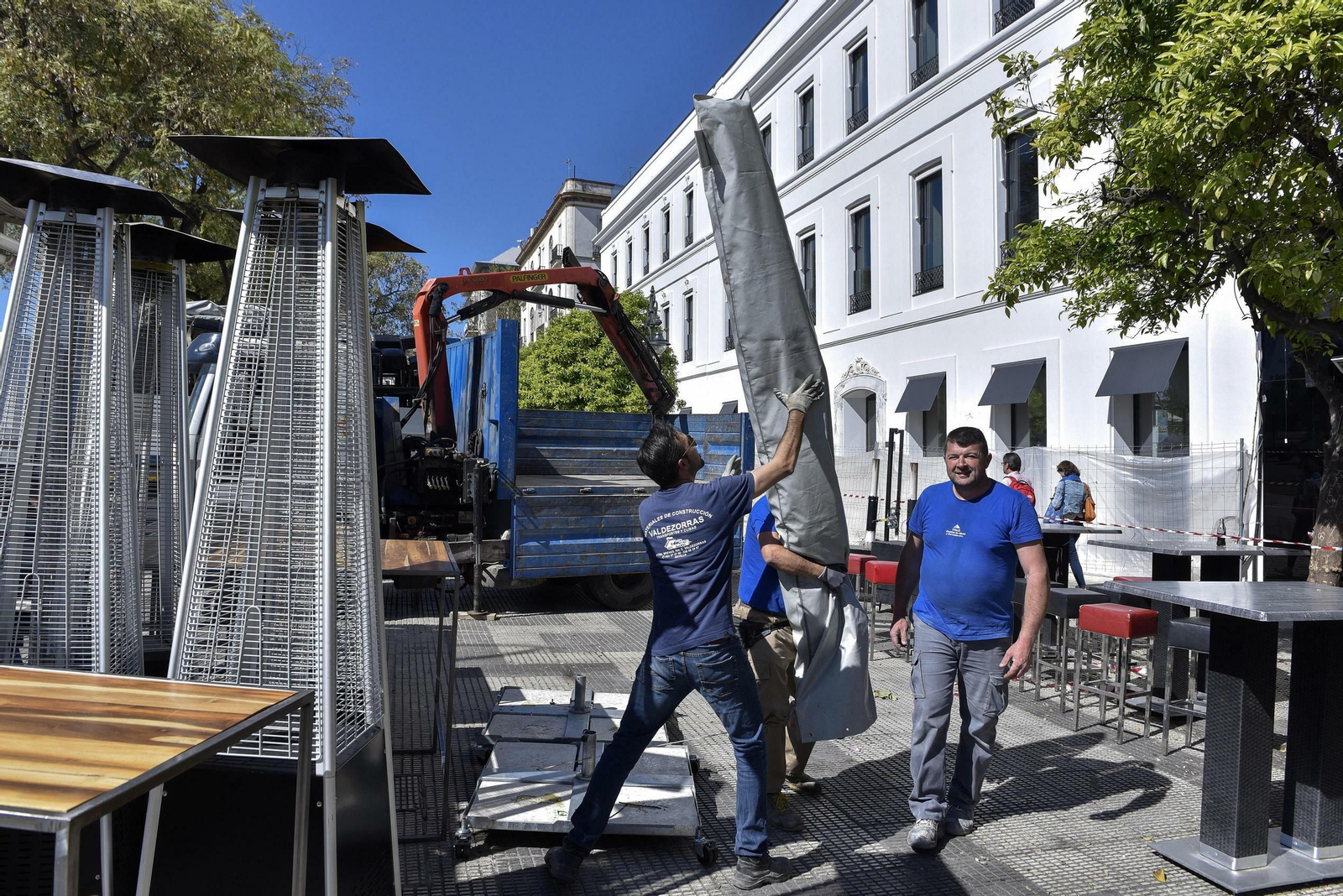 Varios operarios retiran una sombrilla en uno de los bares del Paseo Colón.