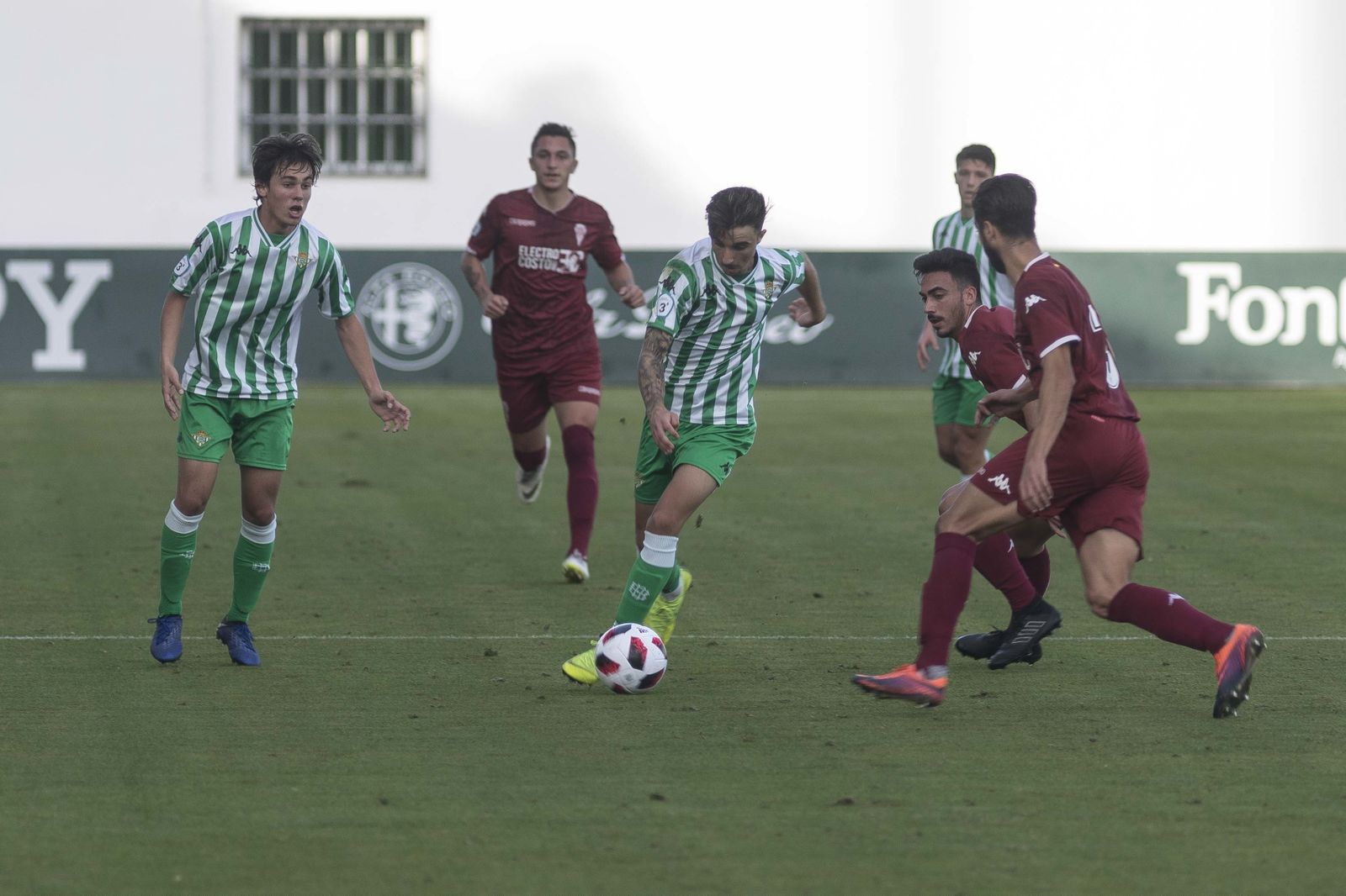 Un jugador bético conduce el balón ante varios cordobesistas.
