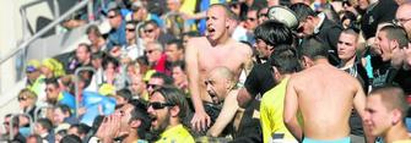 1. Temperatura casi veraniega en el Ramón de Carranza, por lo que se vieron seguidores sin camisetas para aguantar el sofocante calor. 2. Algunos aficionados alzaron sus bufandas a pesar de la pésima temporada del equipo, tratando de no perder el optimismo. 3. Fue una tarde de gorritos de papel para que el sol no diera algún susto. Para los que vienen de Tribuna, el recuerdo de la visera estuvo muy presente. 4. Imagen de la mitad de Tribuna que todavía continúa en pie. La otra parte de la grada ha caído y, con ella, se va buena parte de la centenaria historia del club. 5. Papelillos antes del inicio del encuentro para tratar de arropar a los jugadores en un encuentro de enorme importancia. 	(Fotos: Jesús Marín)