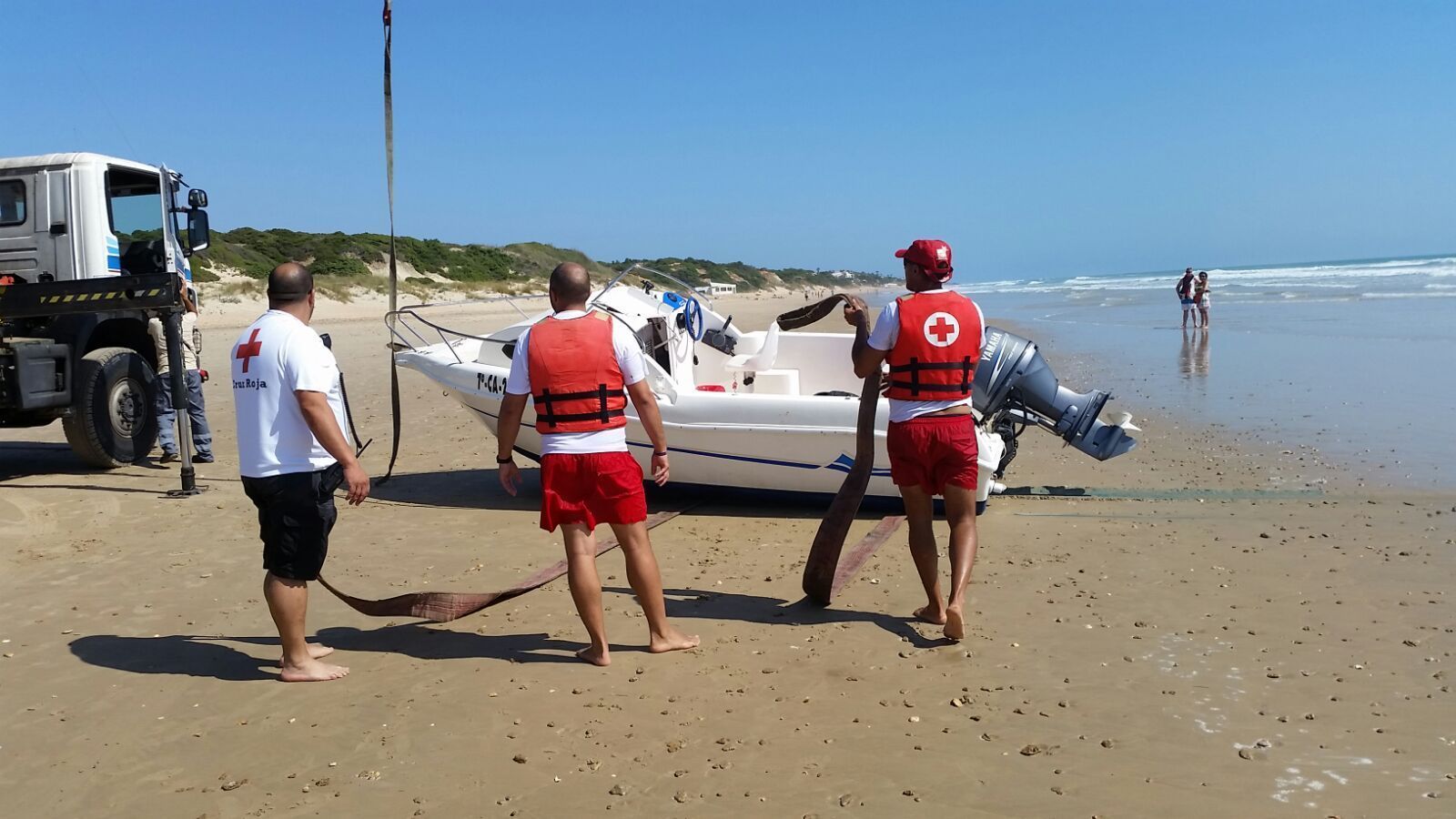 Miembros de Cruz Roja colaboran en el rescate de una embarcación en La Barrosa durante el presente verano.