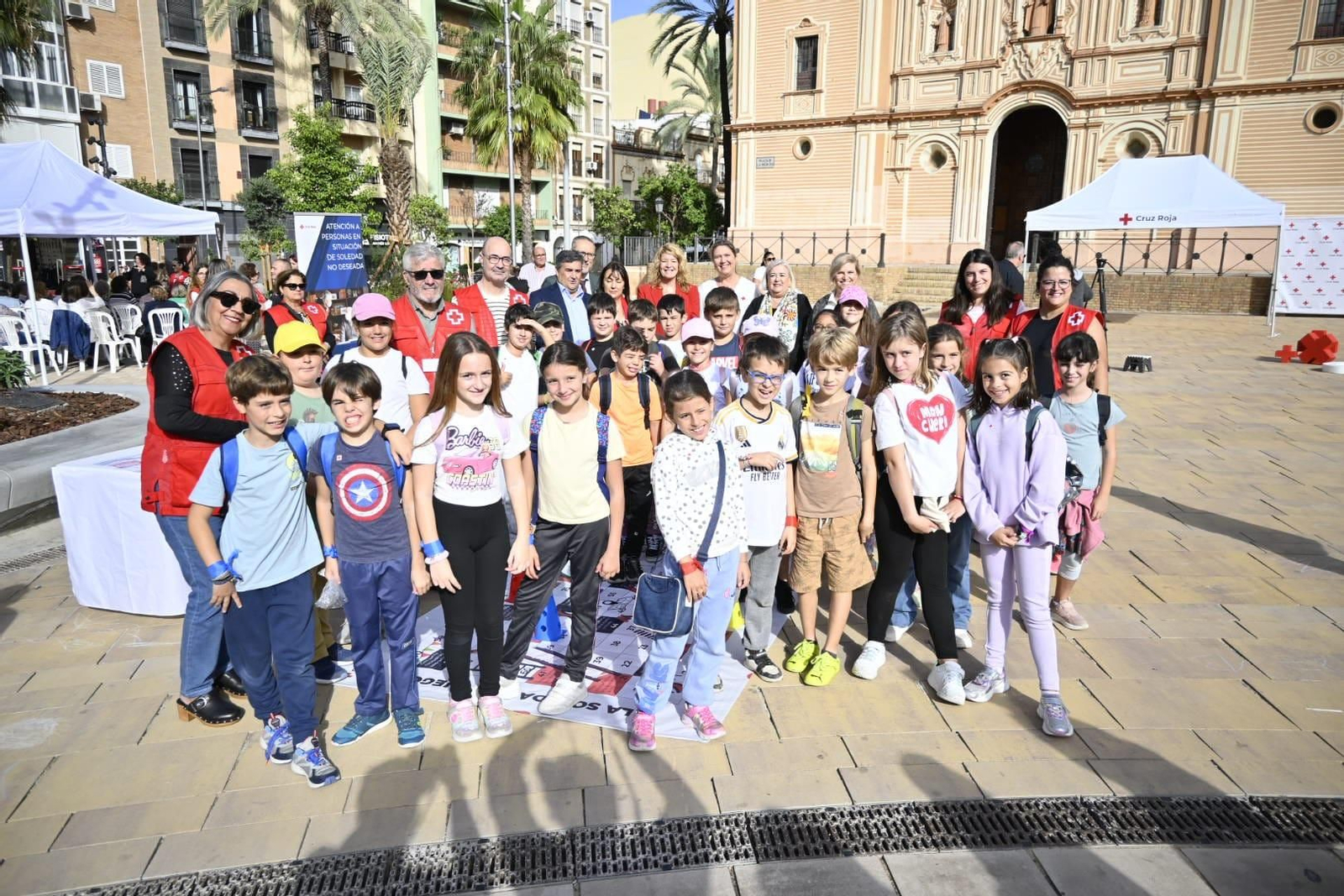 Representantes institucionales junto a uno de los colegios que han asistido al Día de la Banderita de Cruz Roja en la Plaza de la Merced.