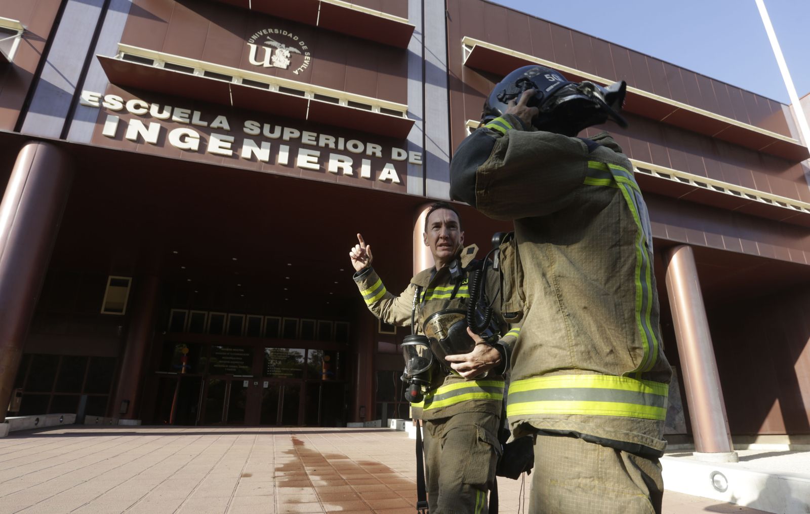 Dos bomberos dialogan tras la intervención en el incendio de la Escuela Superior de Ingeniería.