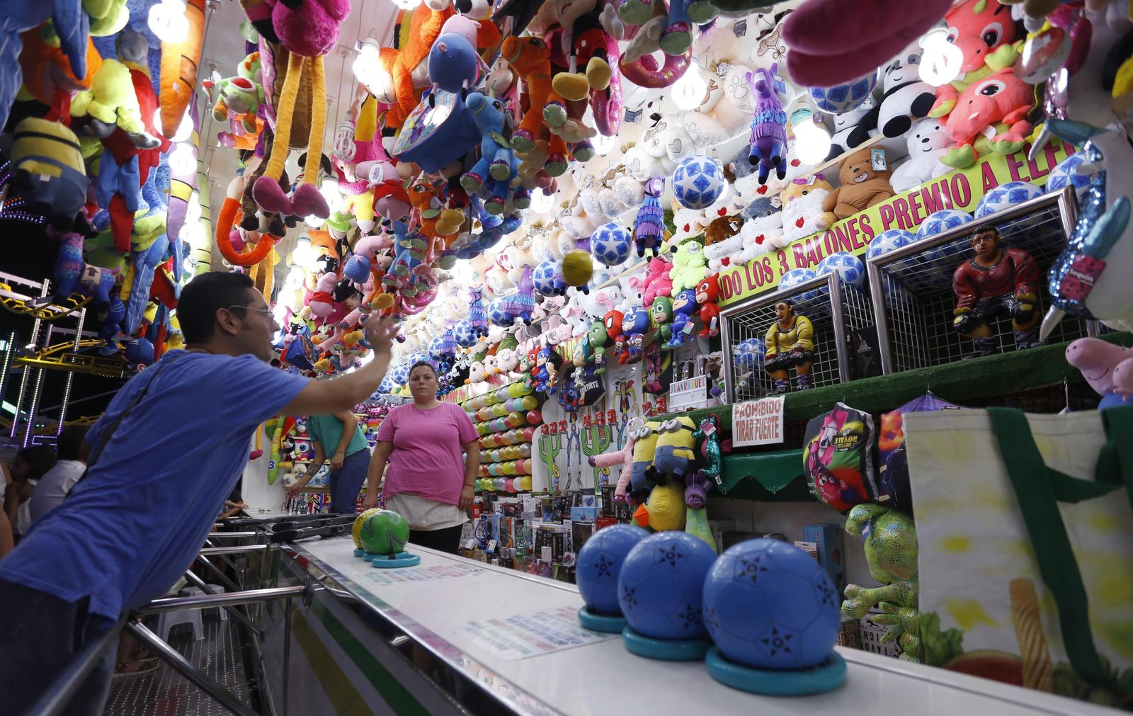 Un hombre prueba suerte en un puesto de un feriante.