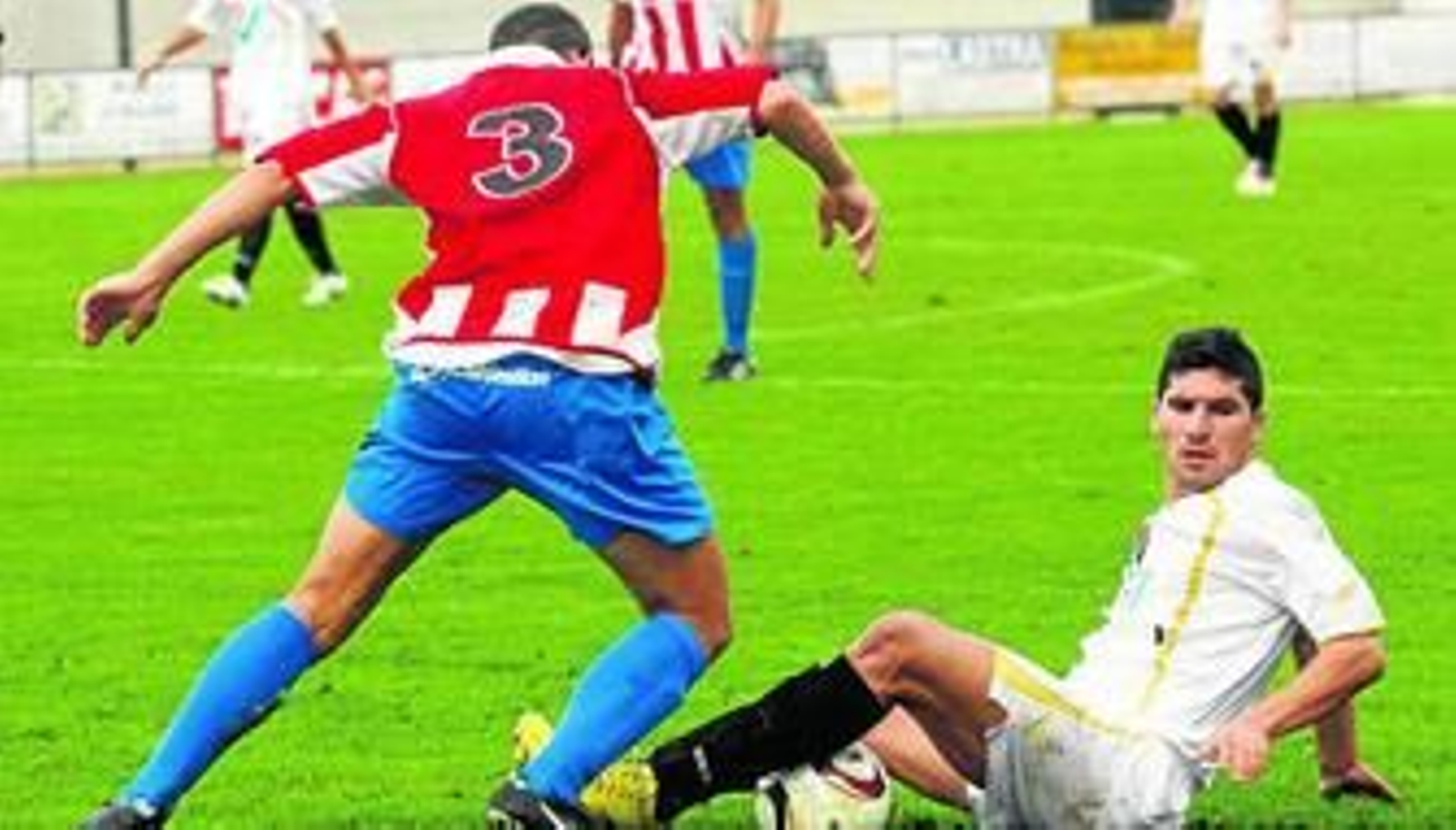 El armillero Luis busca arrebatarle el cuero a un jugador del San Pedro que lo retiene en el suelo.