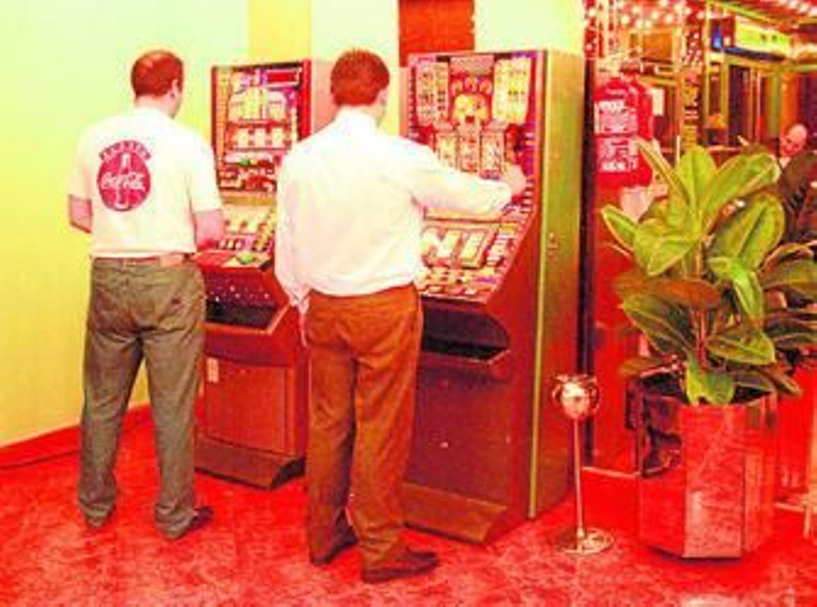 Dos hombres juegan a las máquinas tragaperras en un bar.