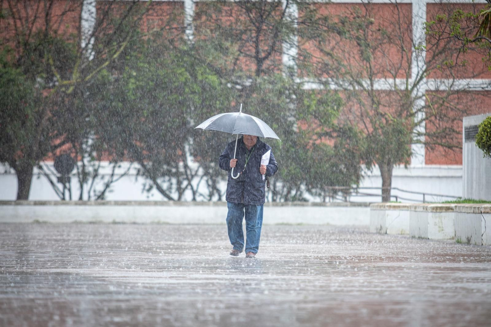 Un hombre pasea por la calle mientras llueve.