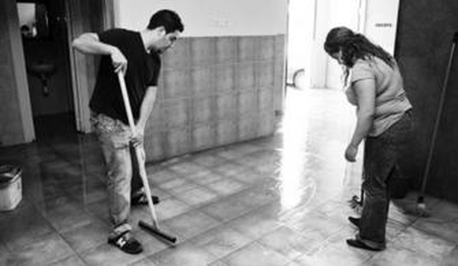 Dos vecinos sacan agua fuera de su casa tras la riada del pasado 21 de noviembre.