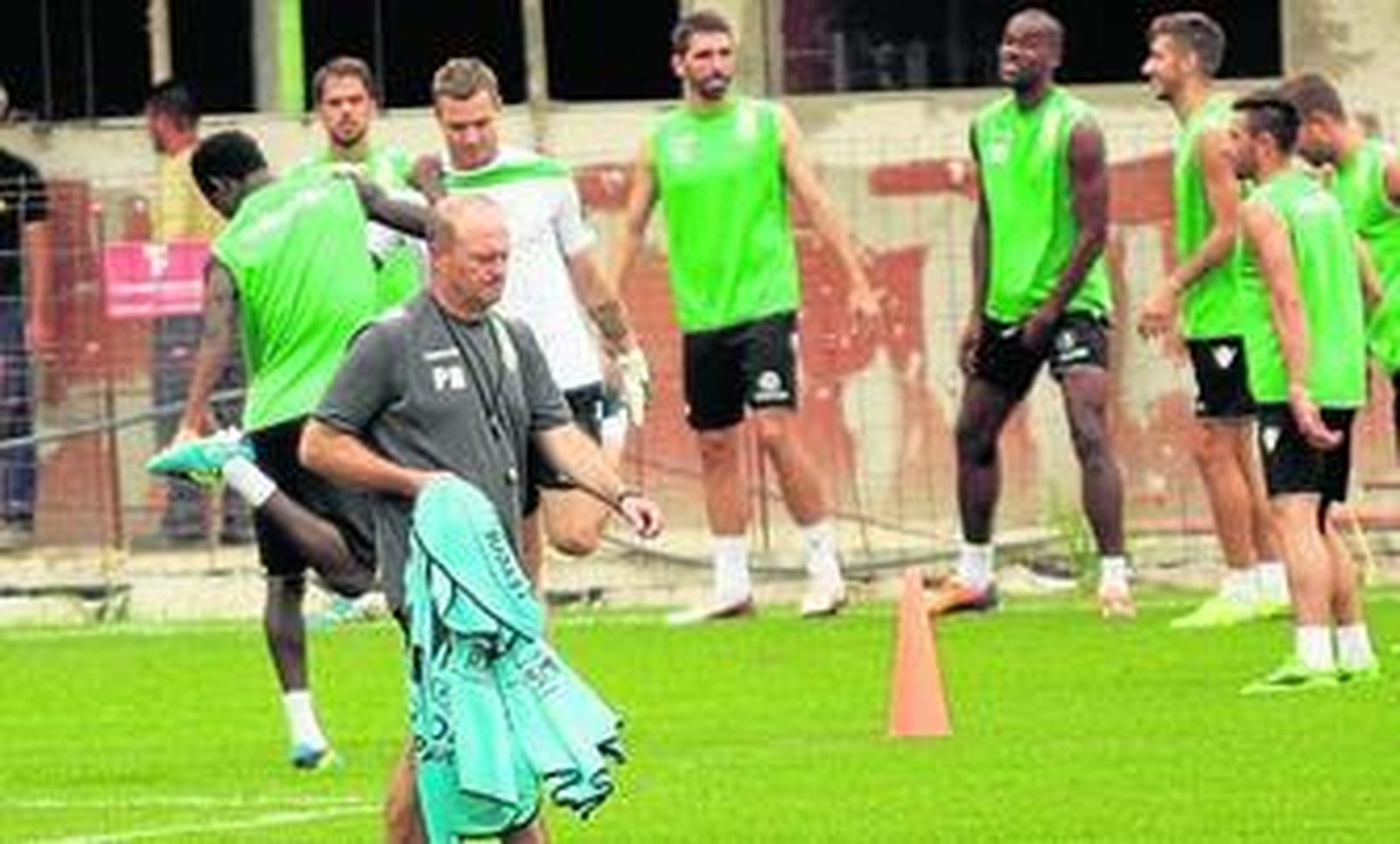 Pepe Mel, con gesto serio, se dispone a repartir los petos mientras sus futbolistas finalizan los primeros estiramientos de la mañana.
