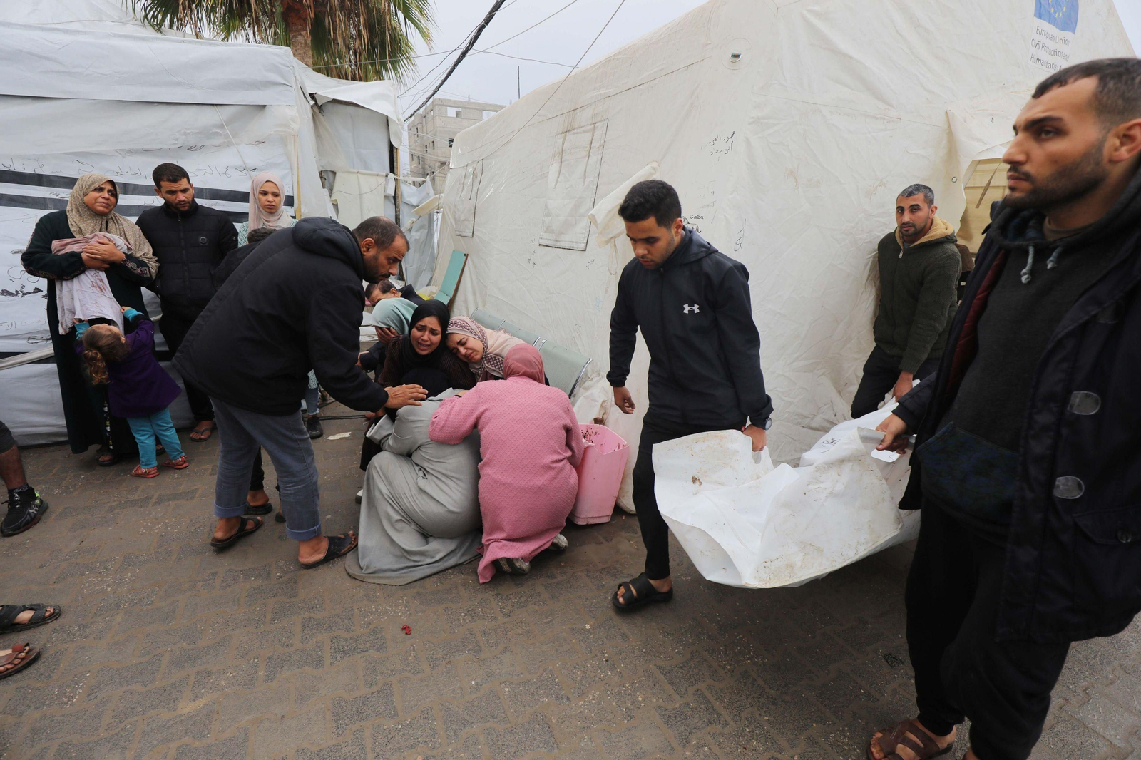 Familiares de los fallecidos en el ataque al campo de refugiados de Al Maghazi lloran mientras esperan recibir sus cuerpos en el hospital El Najar.