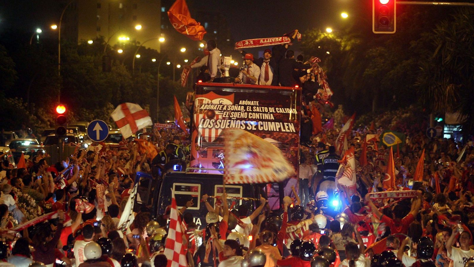 El autobús del Sevilla, rodeados por motoristas y peatones sevillistas en su paseo triunfal.