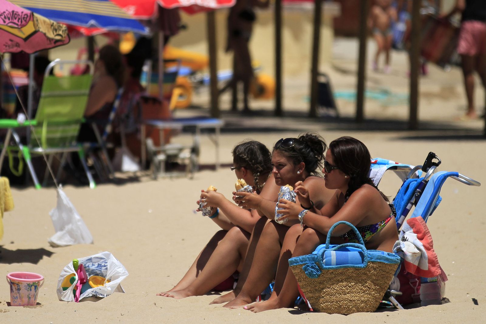 Jóvenes comiendo bocadillos en la playa.