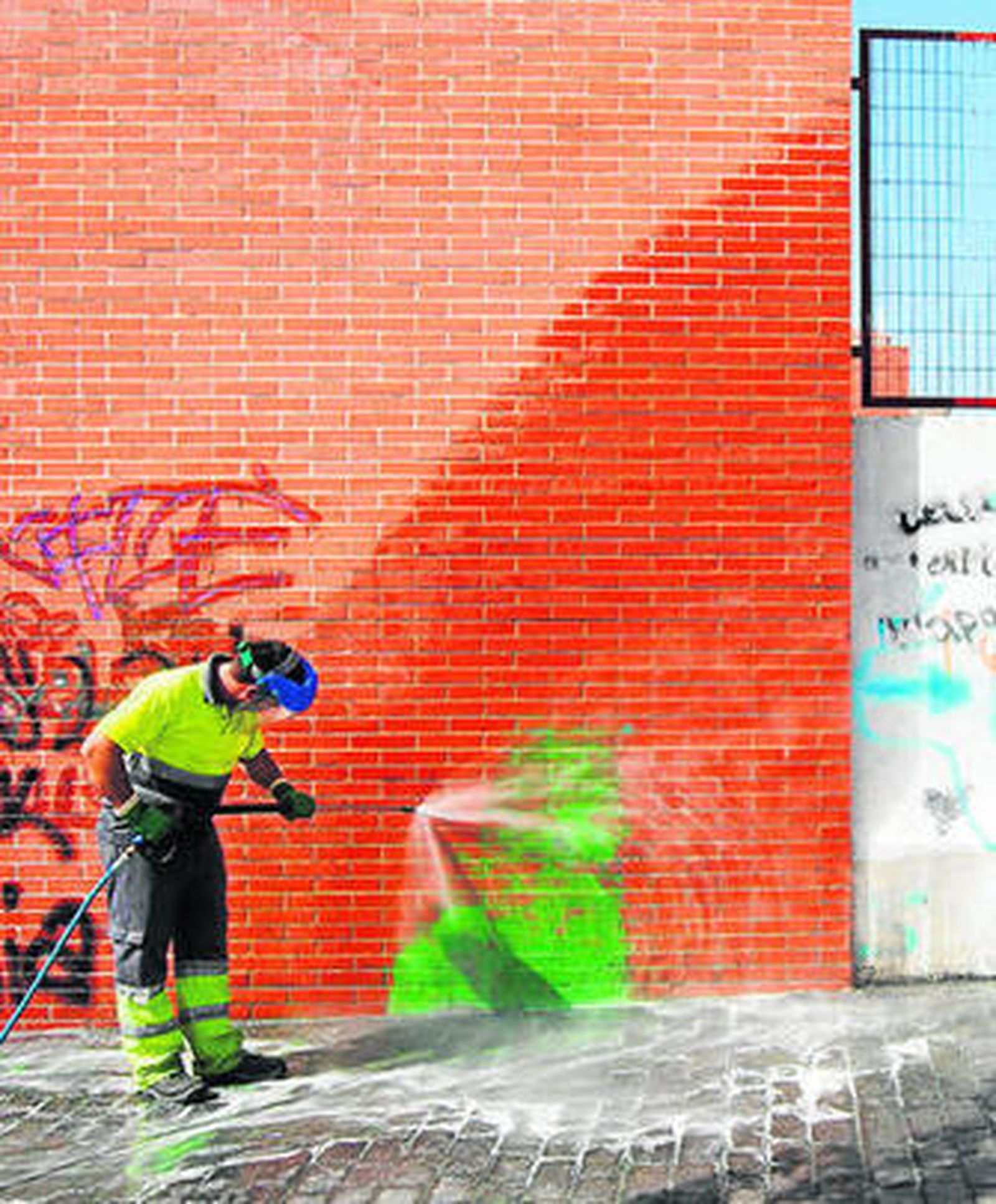 Un operario elimina una pintada de una pared.