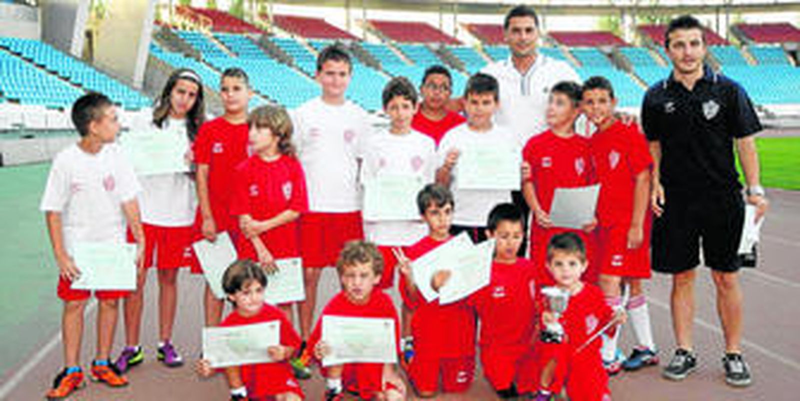 Francisco, técnico del Almería B, y David Rojas, hijo del mítico jugador rojiblanco Juan Rojas, posan junto a los críos del colegio Indalo.