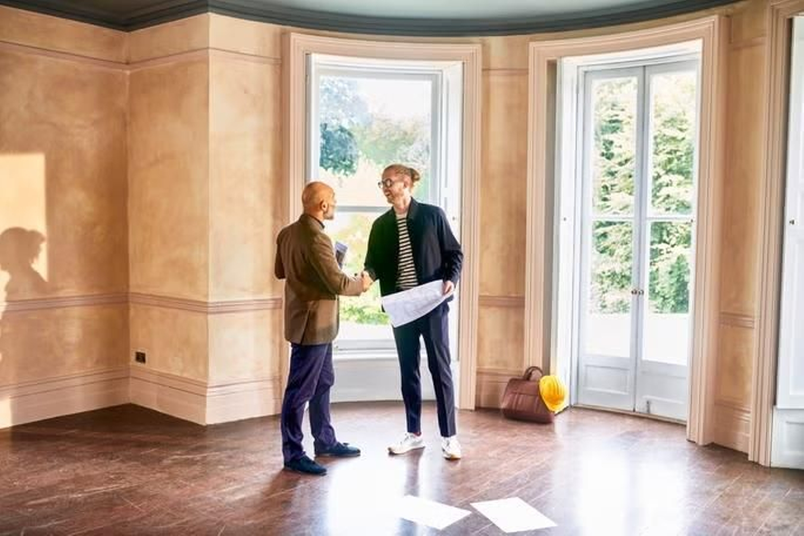 Dos personas sellan la compran de un piso con un apretón de manos.