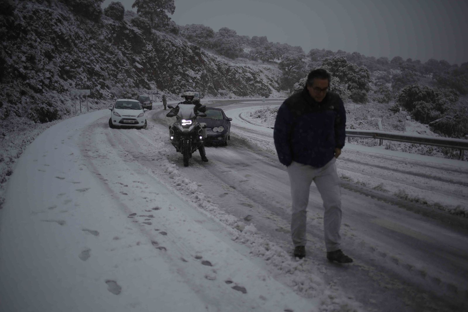 Un conductor pasea por la carretera tras quedar bloqueado su vehículo.