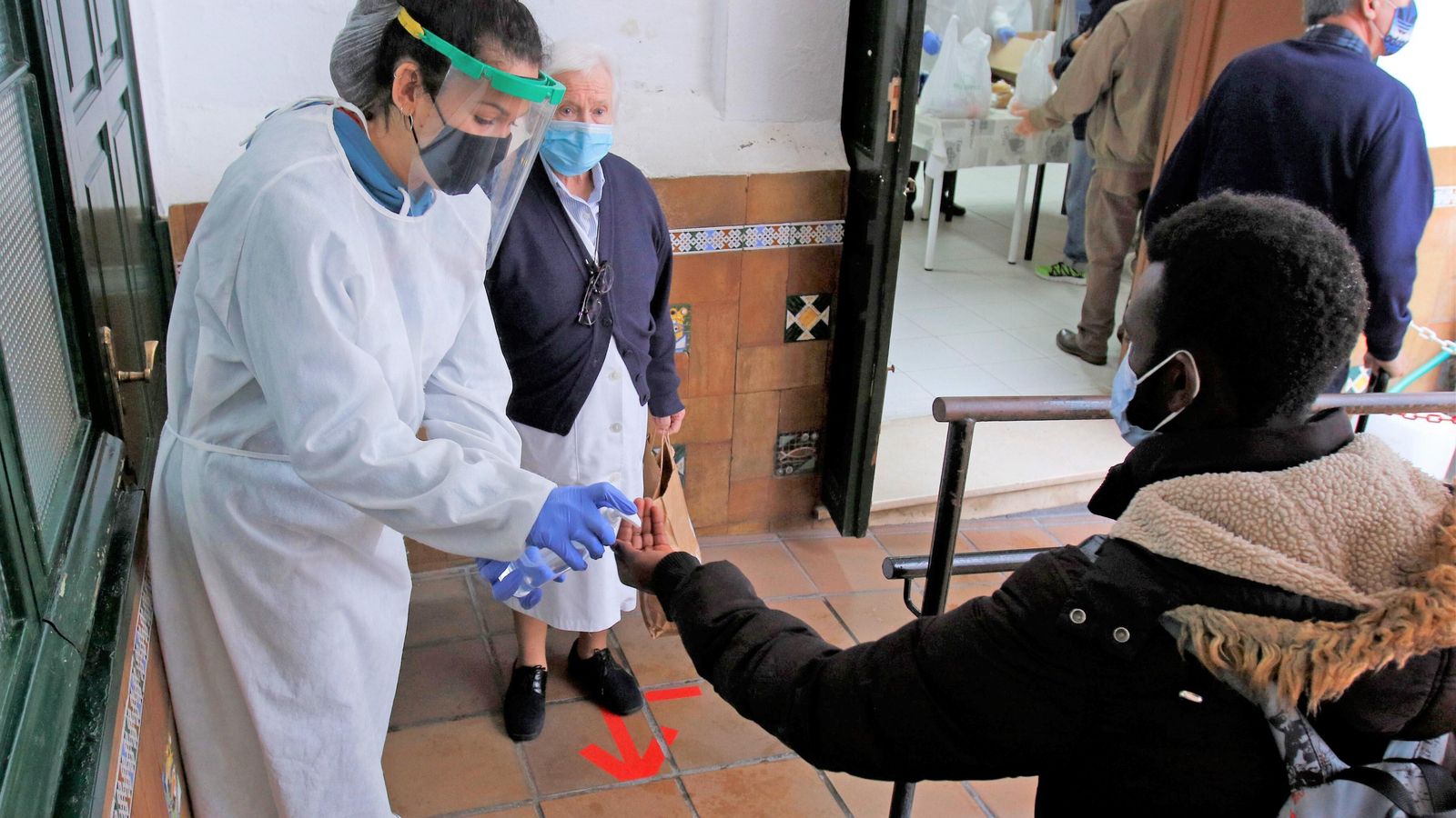 Una voluntaria proporciona gel hidroalcohólico a un usuario africano.