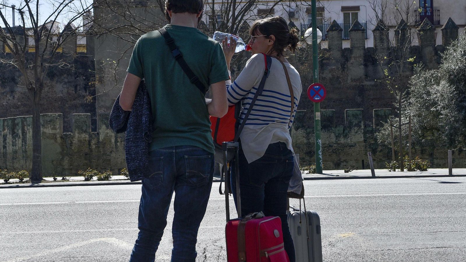 Jóvenes con maletas ante la Muralla de la Macarena.