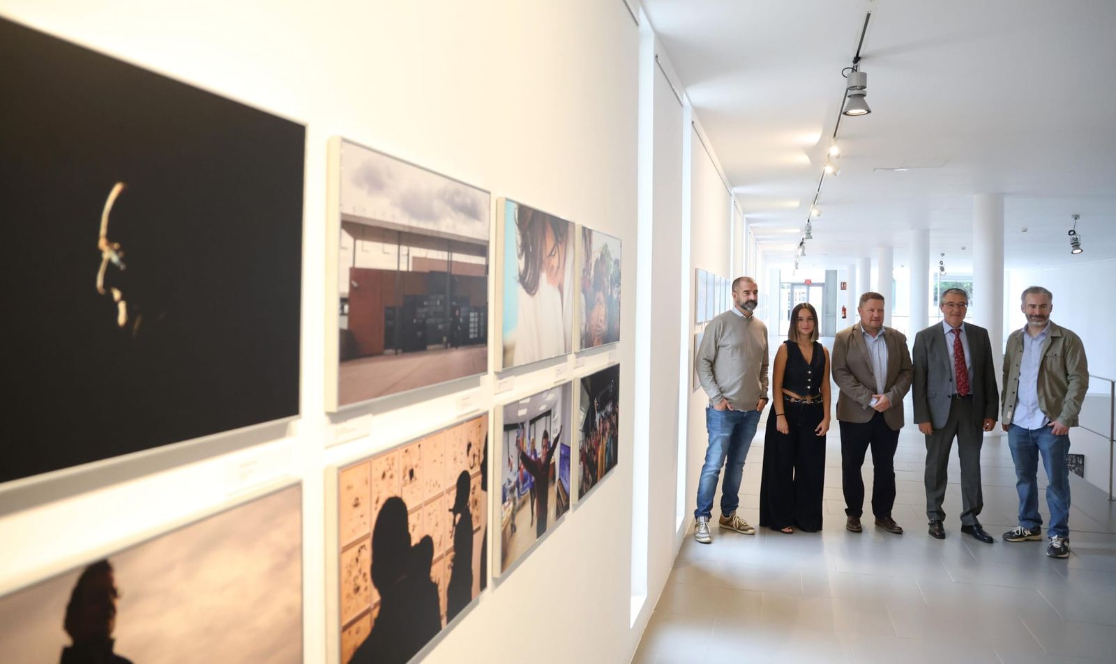 Fotografías en al exposición y, al fondo, sus comisarios acompñados de autoridades.