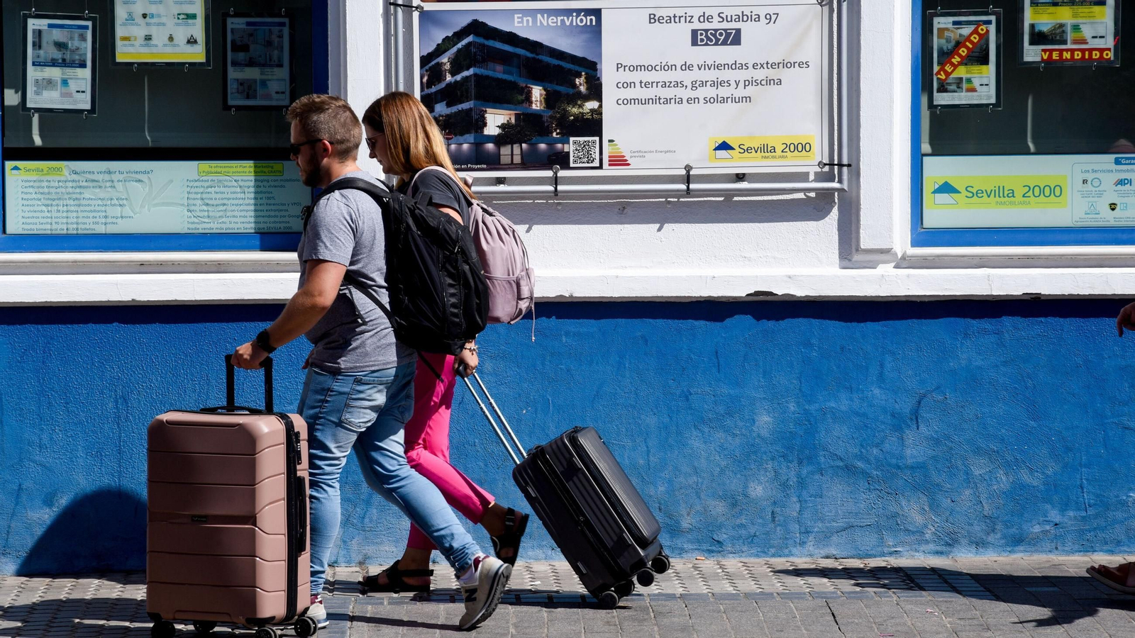 Una pareja pasa por delante de una inmobiliaria