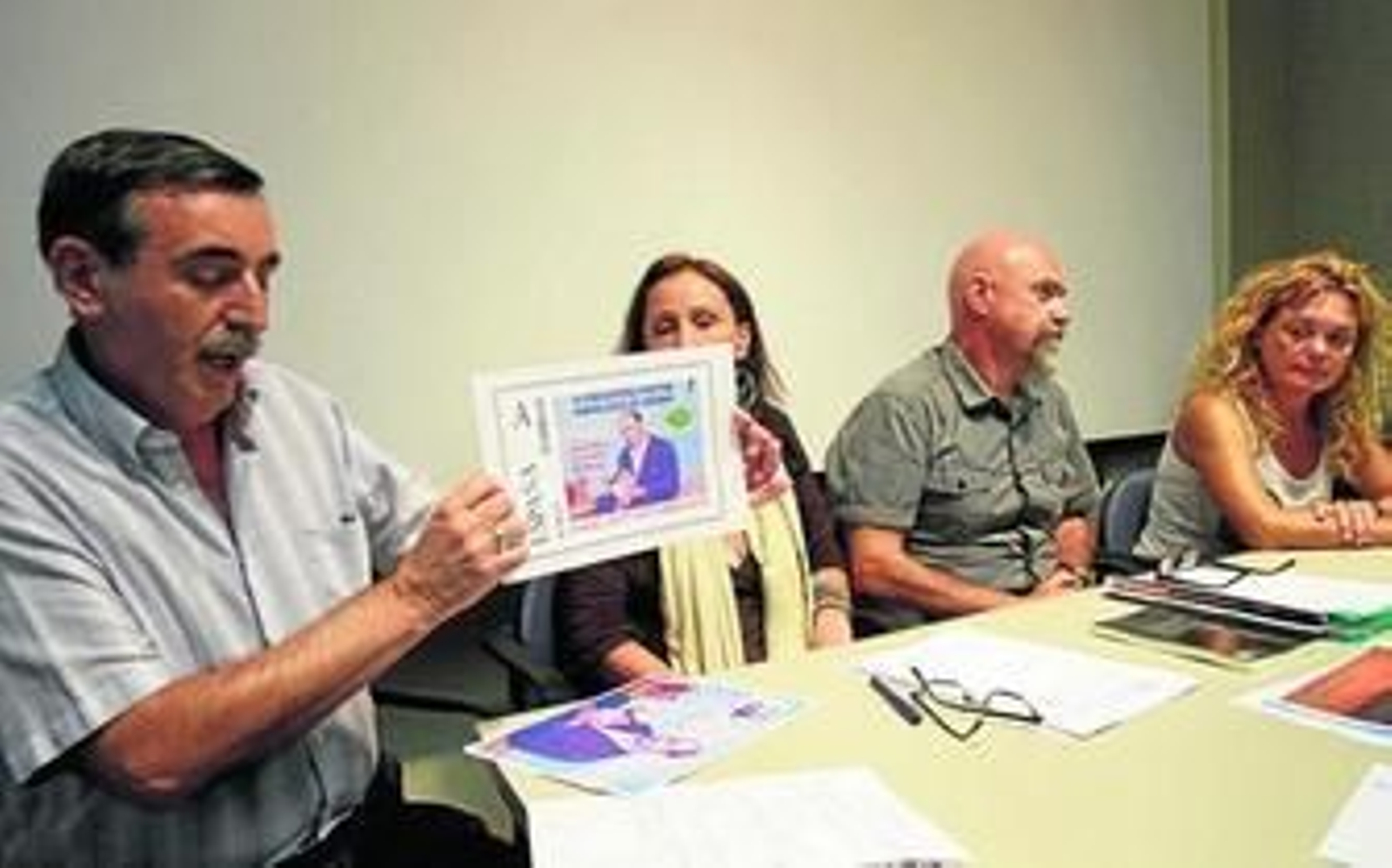 Un miembro de la Sociedad Filatélica Gaditana muestra el sello conmemorativo junto a los organizadores del encuentro poético en Cádiz.