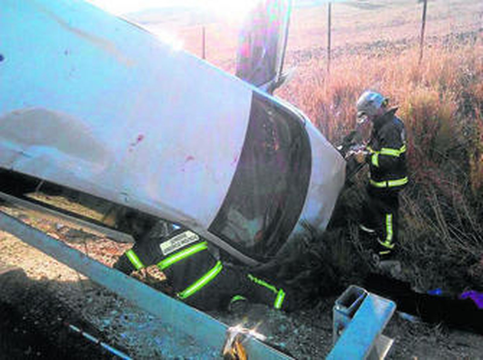 Dos bomberos junto al vehículo tras el accidente.
