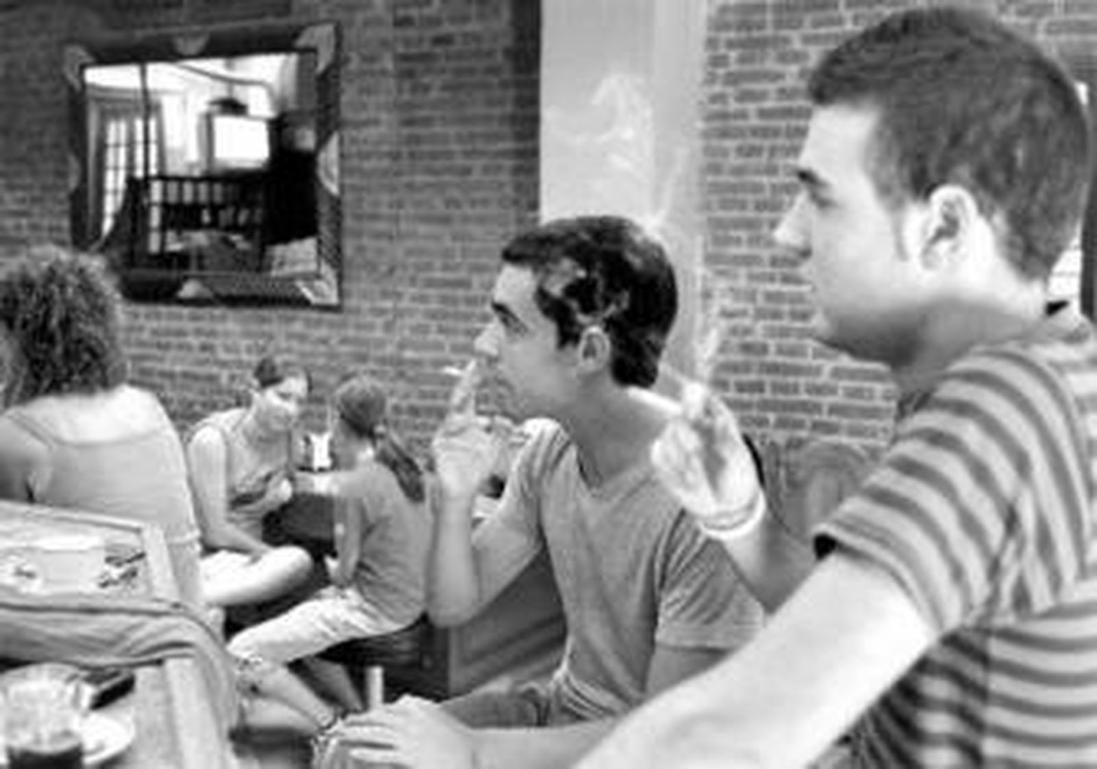 Dos jóvenes fuman dentro de un bar.