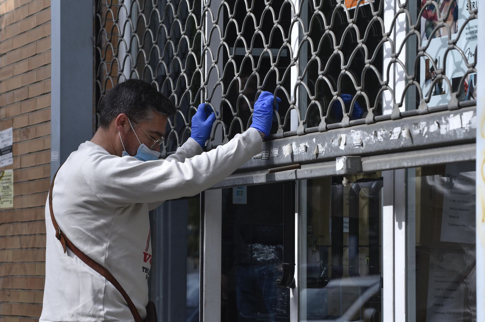 Un autónomo cierra la persiana de su negocio.