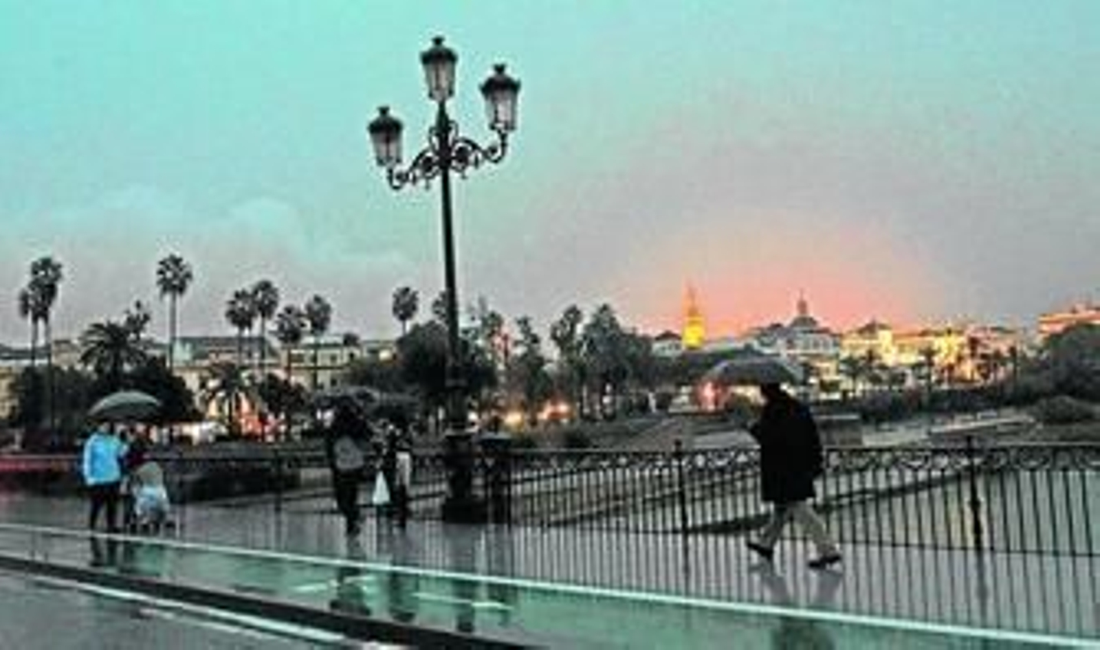 Transeúntes bajo paraguas en el Puente de Triana, ayer.