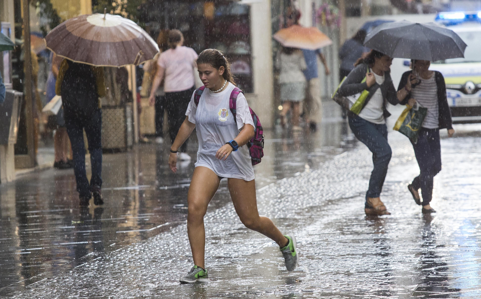 Una joven camina bajo la lluvia en Sevilla.