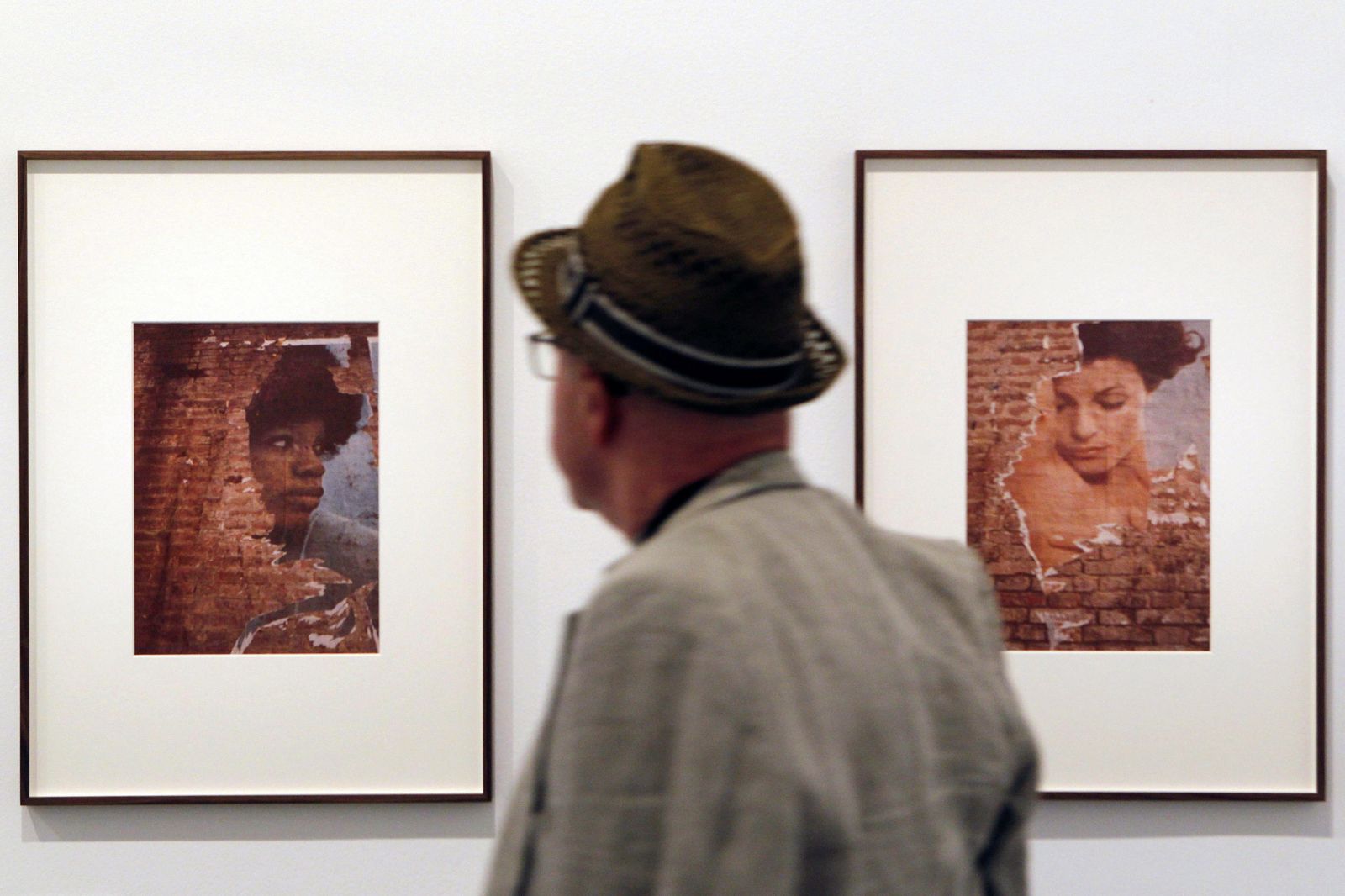 Un hombre observa varias de las fotografías de la muestra.