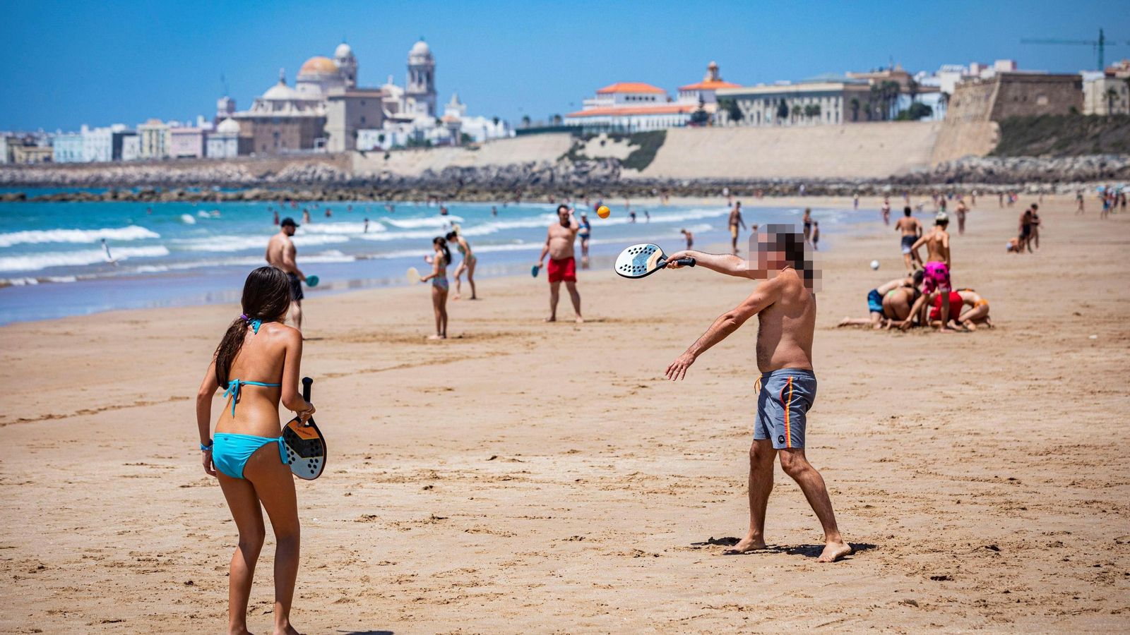 Una joven pareja juega a las palas sin molestar a nadie,  a varios metros de distancia del último bañista.