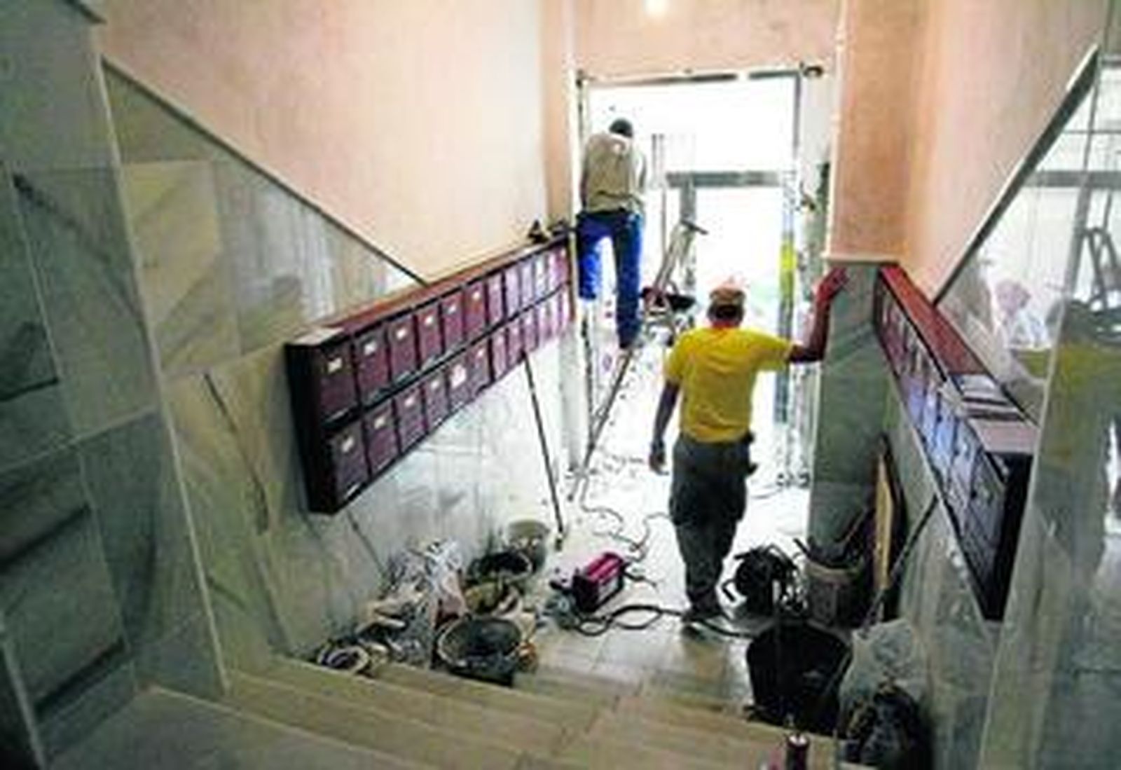 Albañiles trabajan en el acondicionamiento de la entrada principal de un bloque de viviendas.