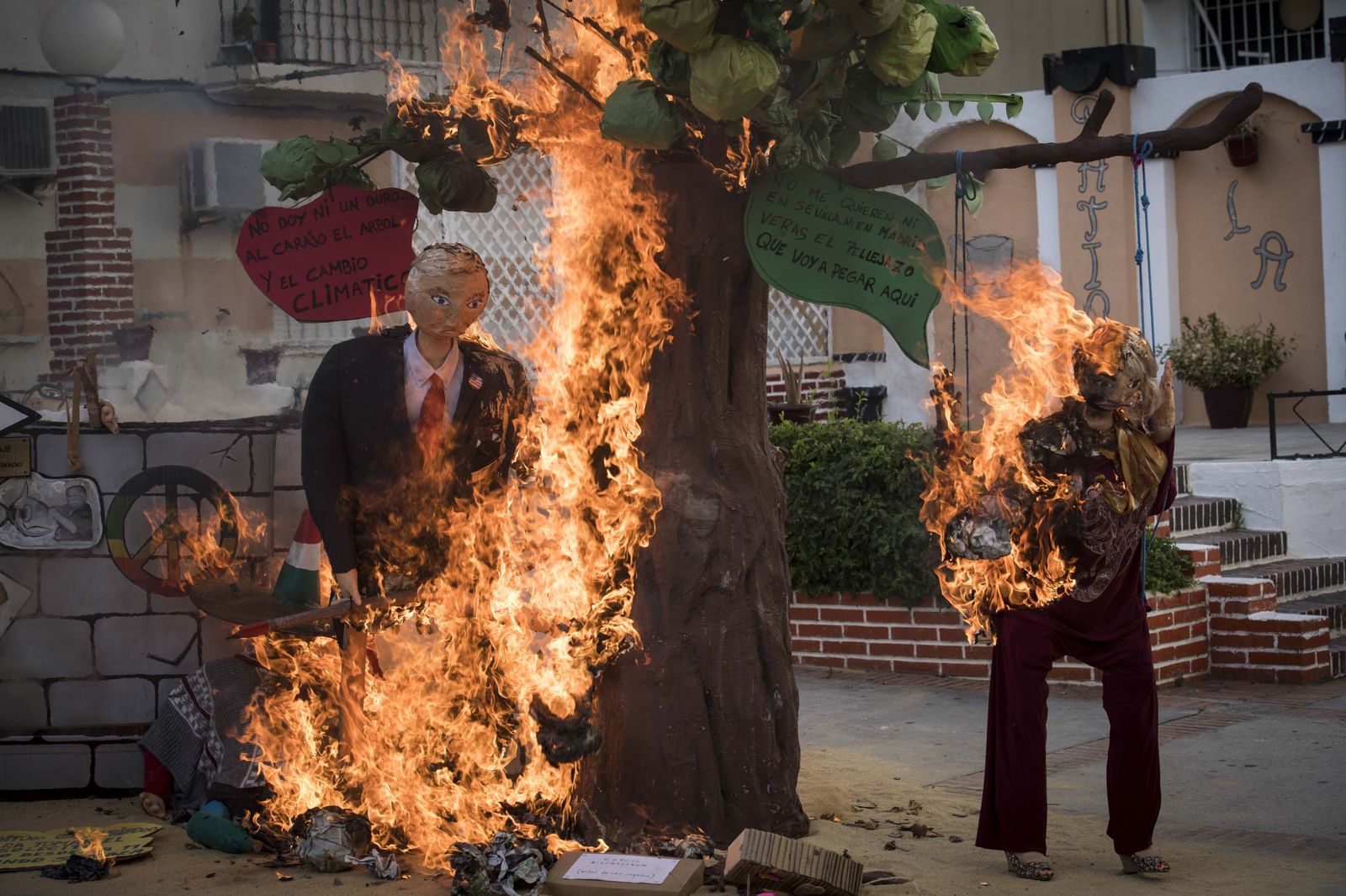 Un Donald Trump contra el cambio climático, cortando un árbol, arde en el patio de la AAVV Tacita de Plata.