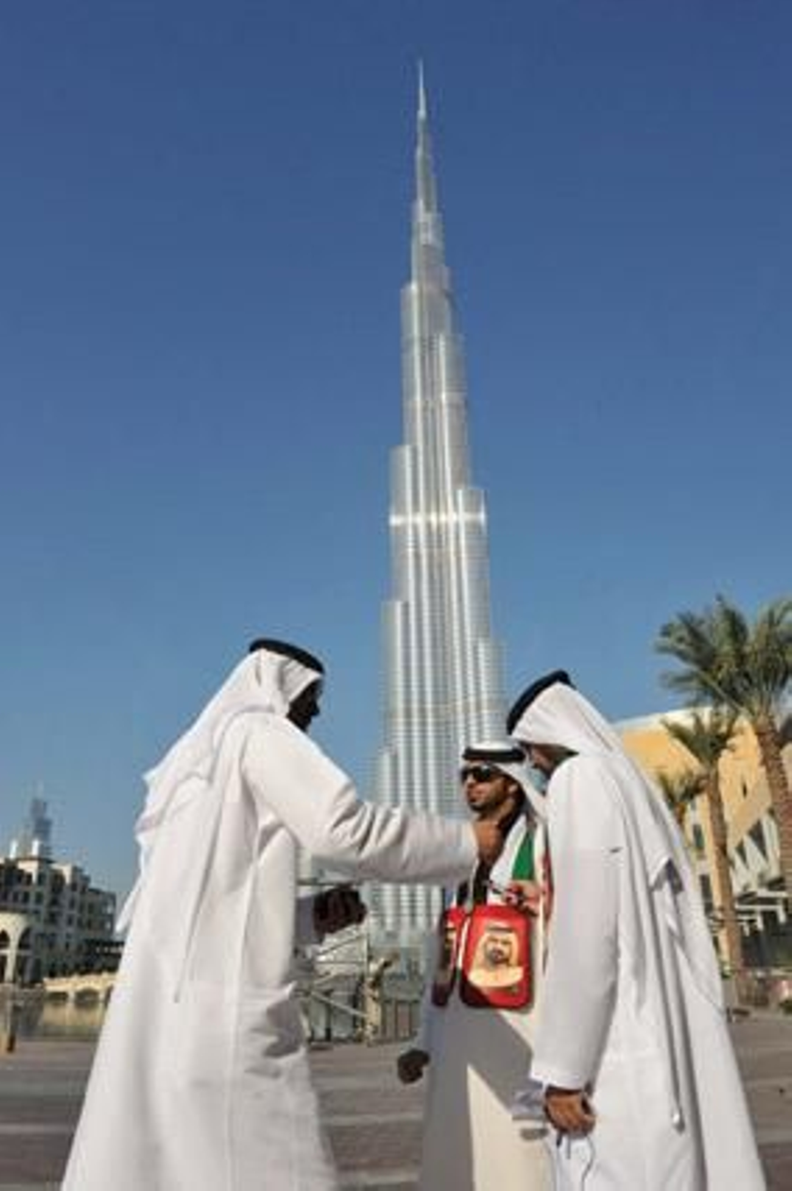 Un grupo de dubaitíes pasea bajo la Burj Dubai. / Efe