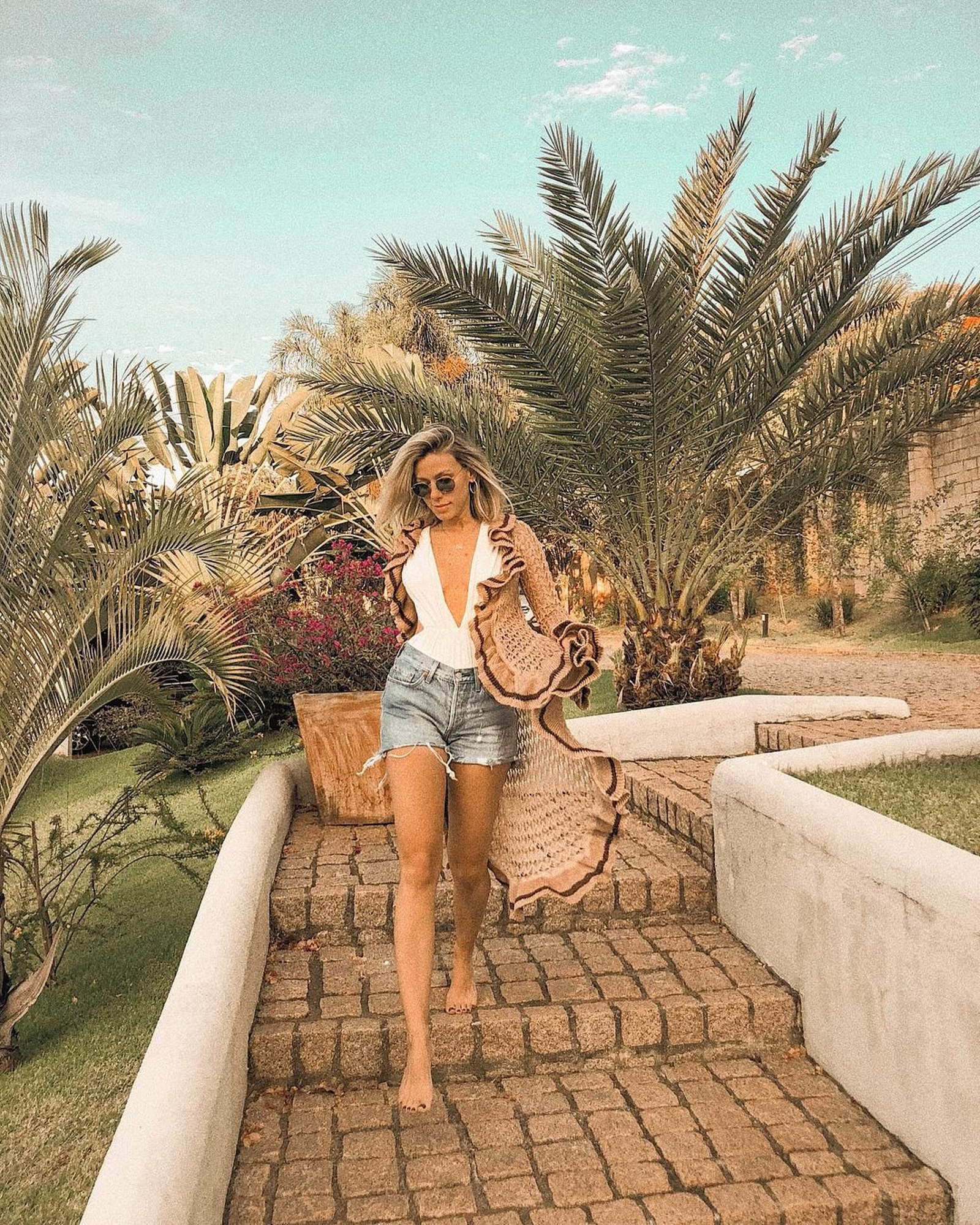 La brasileña Nati Vozza sabe como ir a la playa con estilo y lo hace llevando sobre su bañador blanco unos shorts vaqueros y una chaqueta de hilo con volantes de Galeria Tricot.