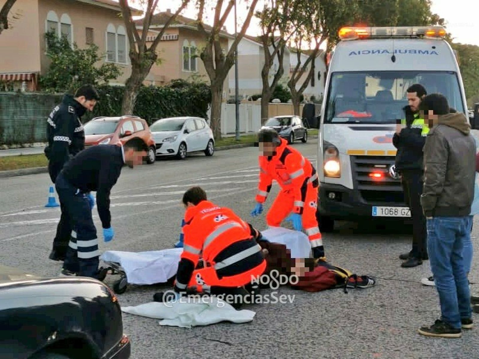 Los servicios sanitarios y la Policía Local asisten al joven herido, en el suelo.