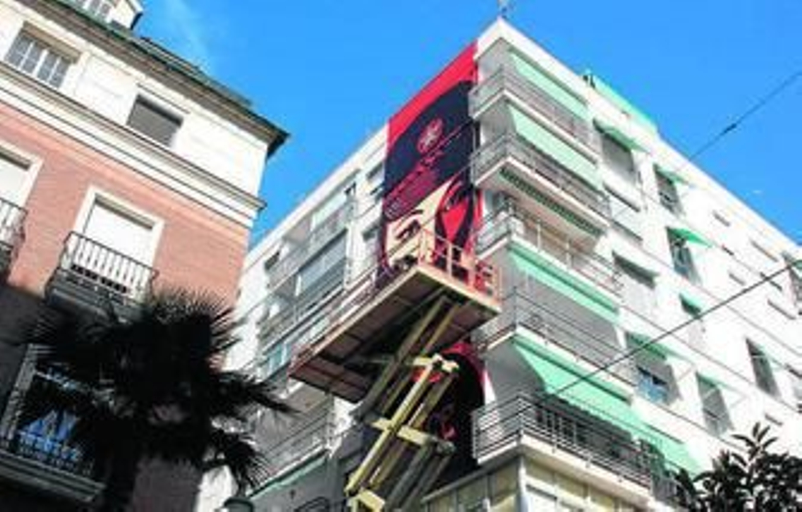 El equipo de Obey subido a la grúa rematando los últimos detalles del mural en la calle Tomás Heredia.