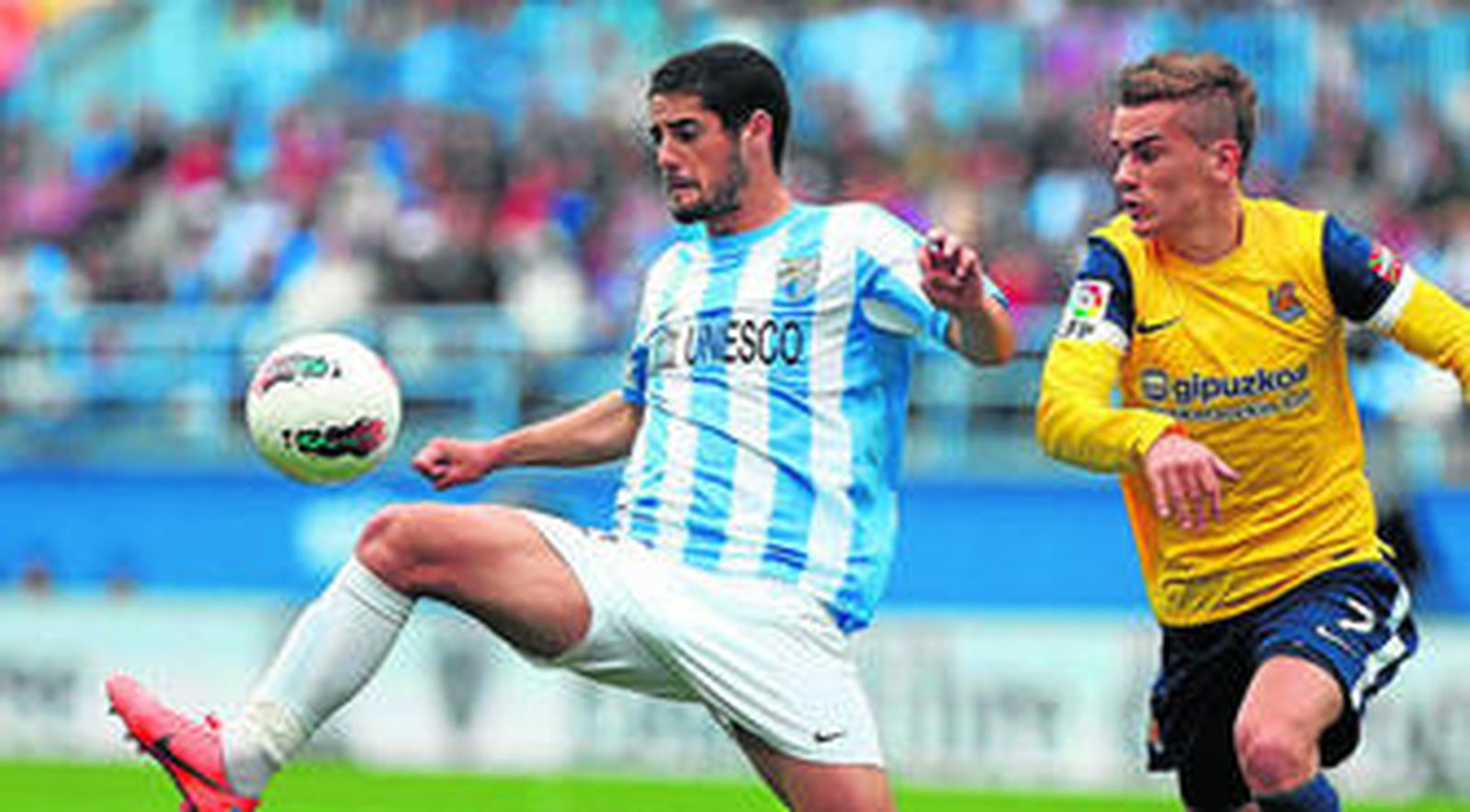 El malaguista Isco, autor del gol de su equipo, controla el esférico en presencia del delantero francés de la Real Sociedad, Griezmann.