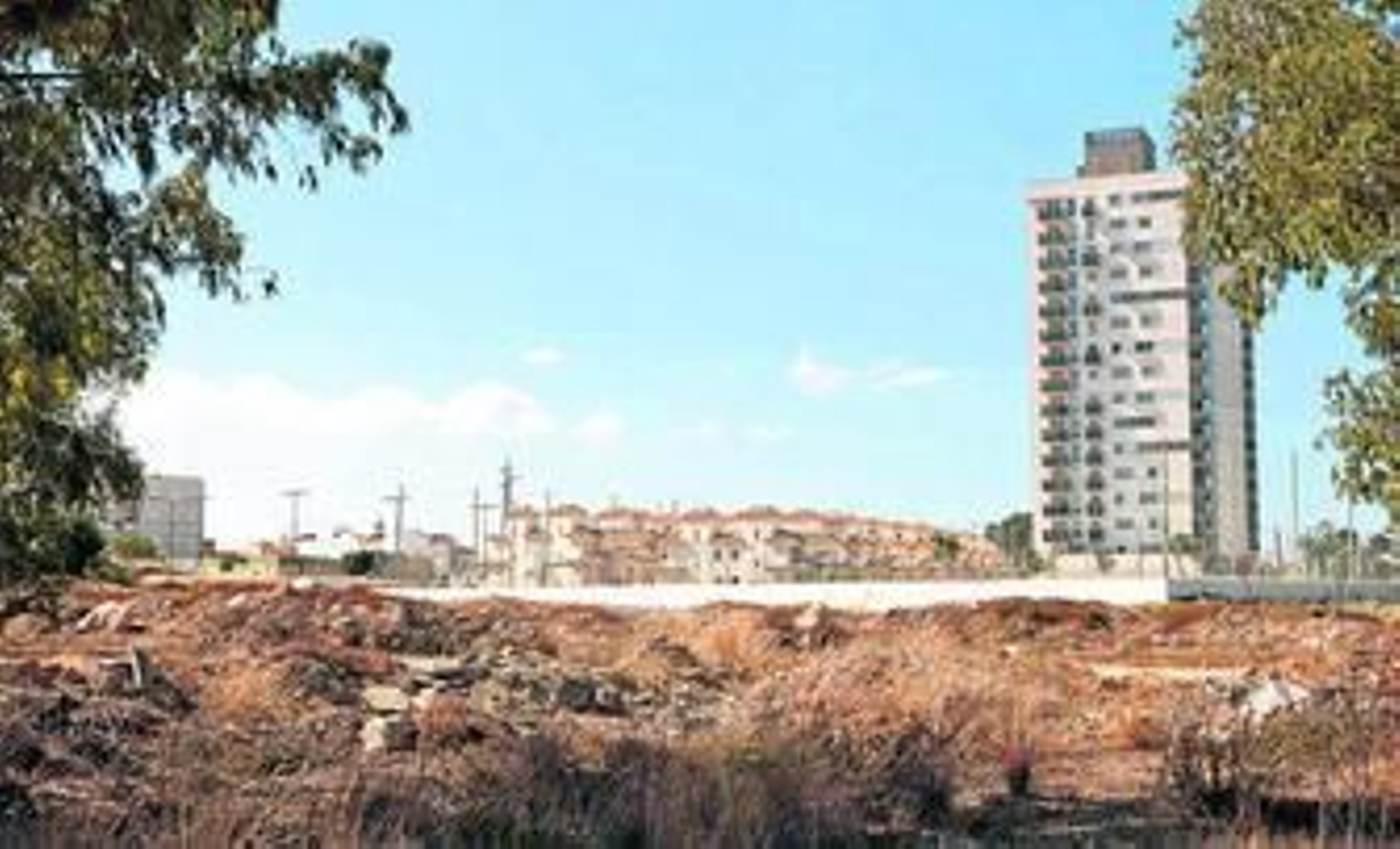 Terrenos de La Casería, con una de las polémicas torres al fondo junto a hileras de unifamiliares.