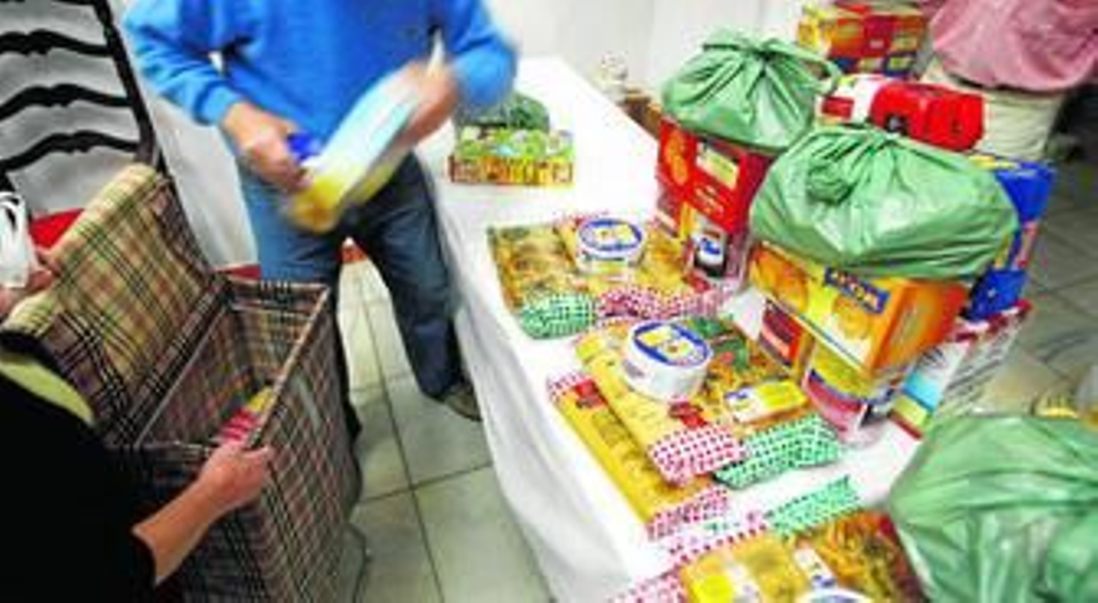 Un voluntario de Cáritas entrega un lote de alimentos a una de las familias que atiende, en una imagen de archivo.