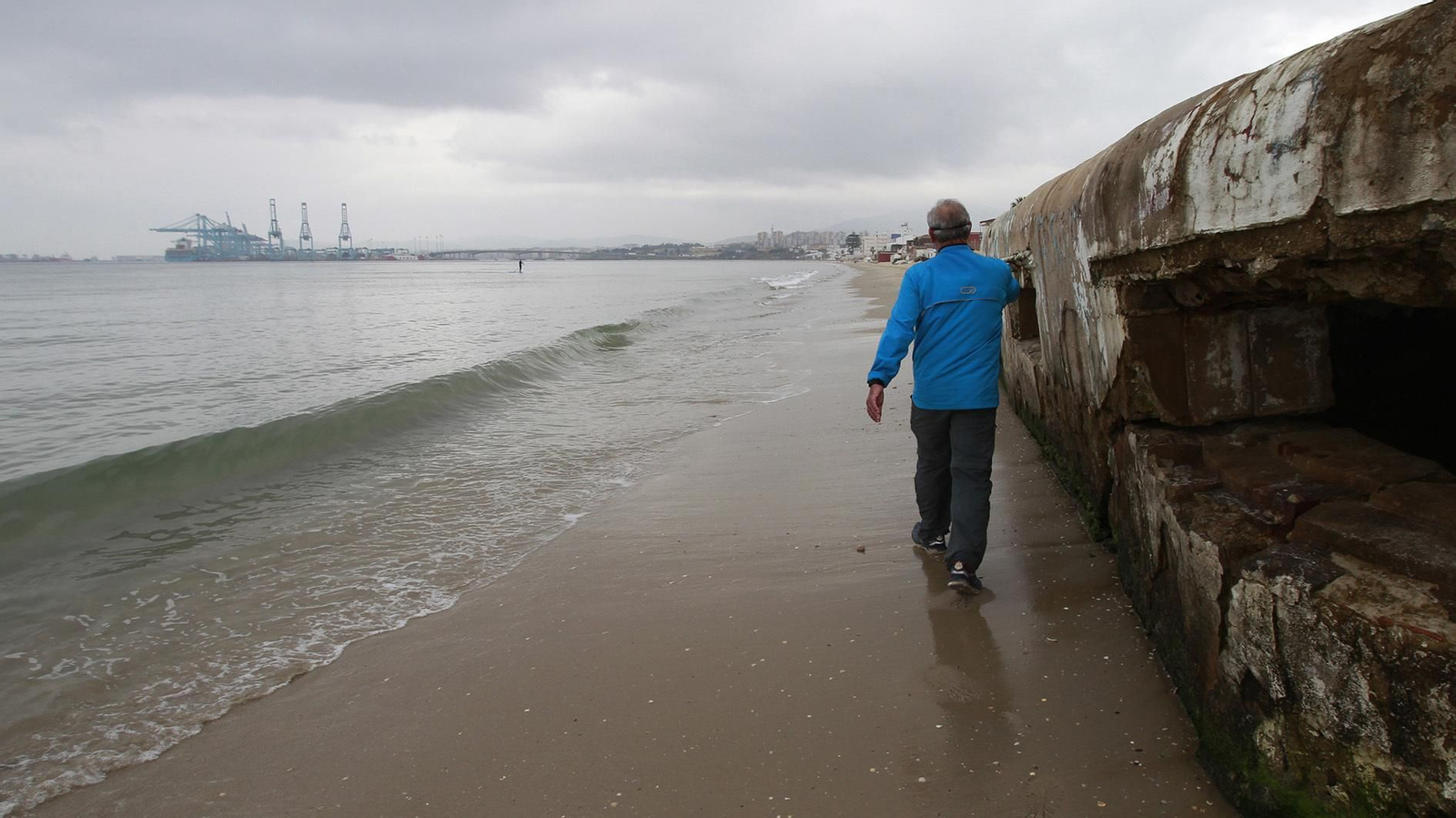Un hombre pasea junto al bunker de la playa del Rinconcillo.