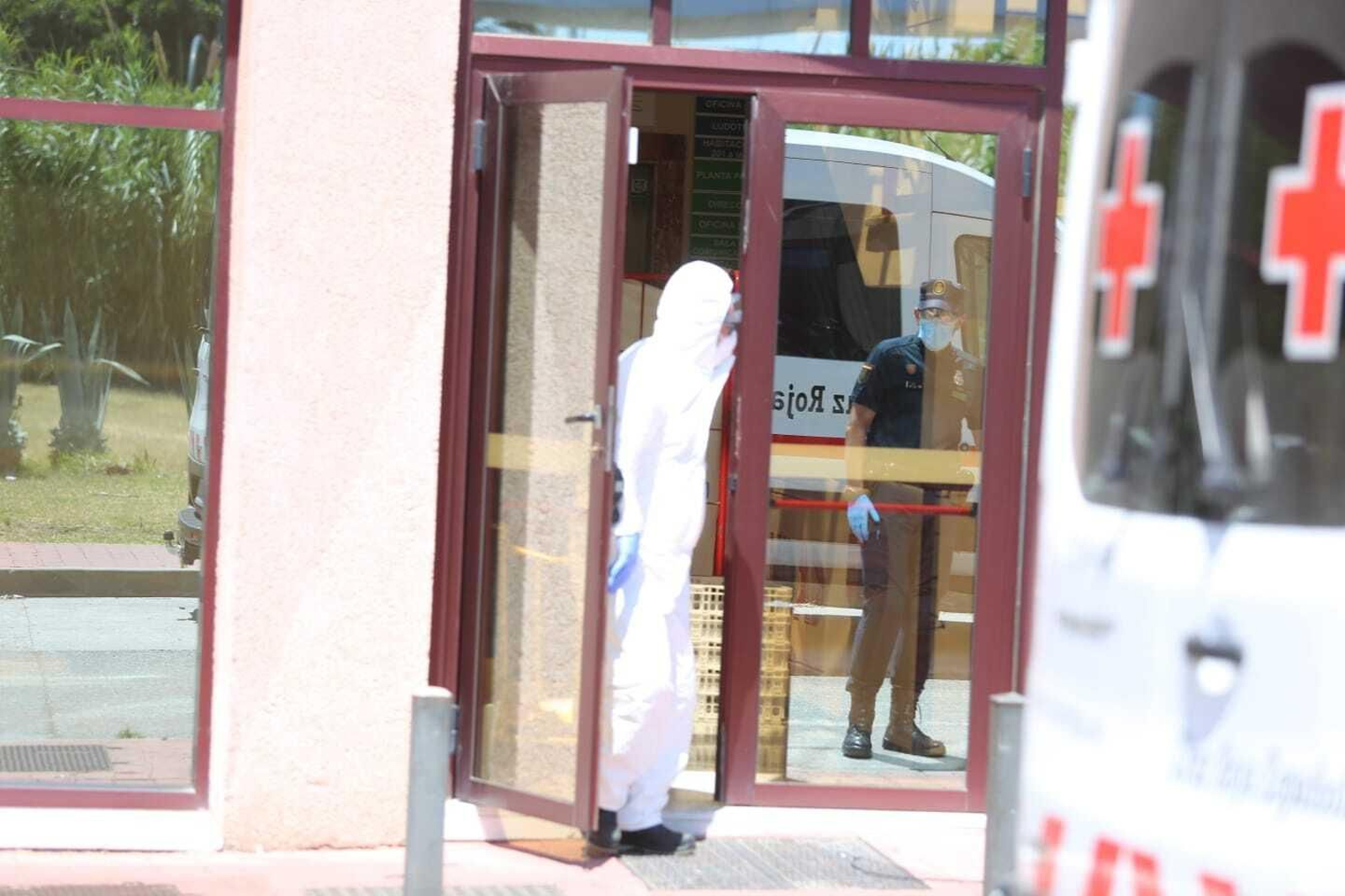 Un trabajador vestido con el equipo de protección y un policía, en el centro de Cruz Roja.
