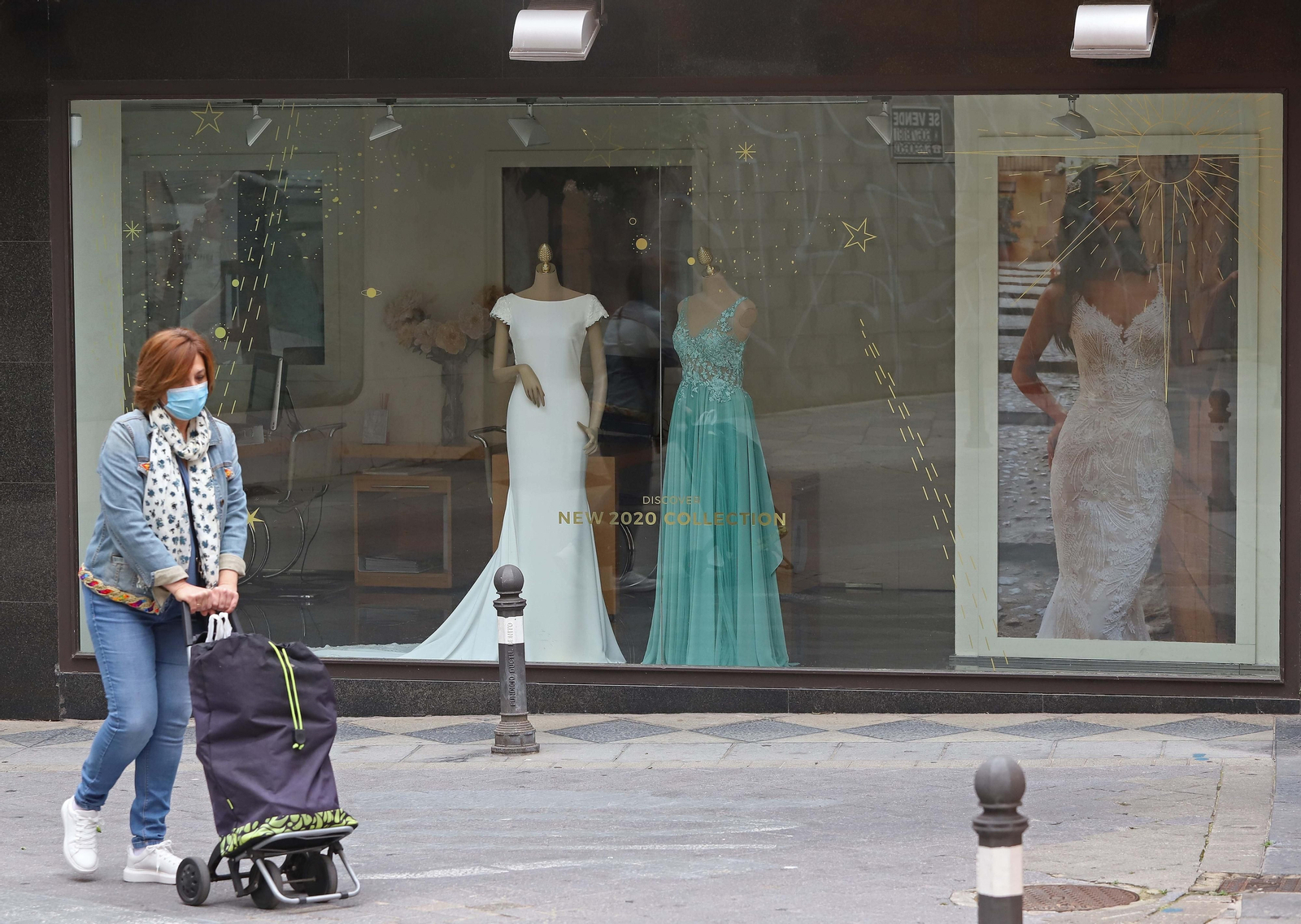 Una mujer camina delante de un negocio de vestidos de novia y acompañantes, en Algeciras.
